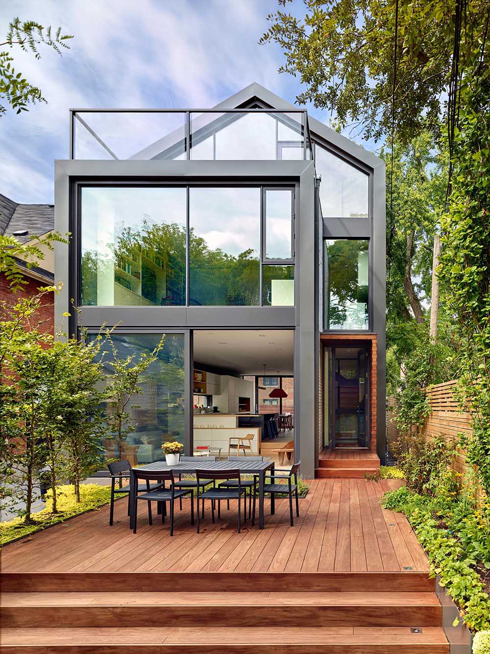 The rear yard is landscaped and features a generously scaled thermally treated ash wood deck, and a few steps down, another zone defined by granite pavers is planted with a row of honey locust trees that offer dappled light and shade in summer.