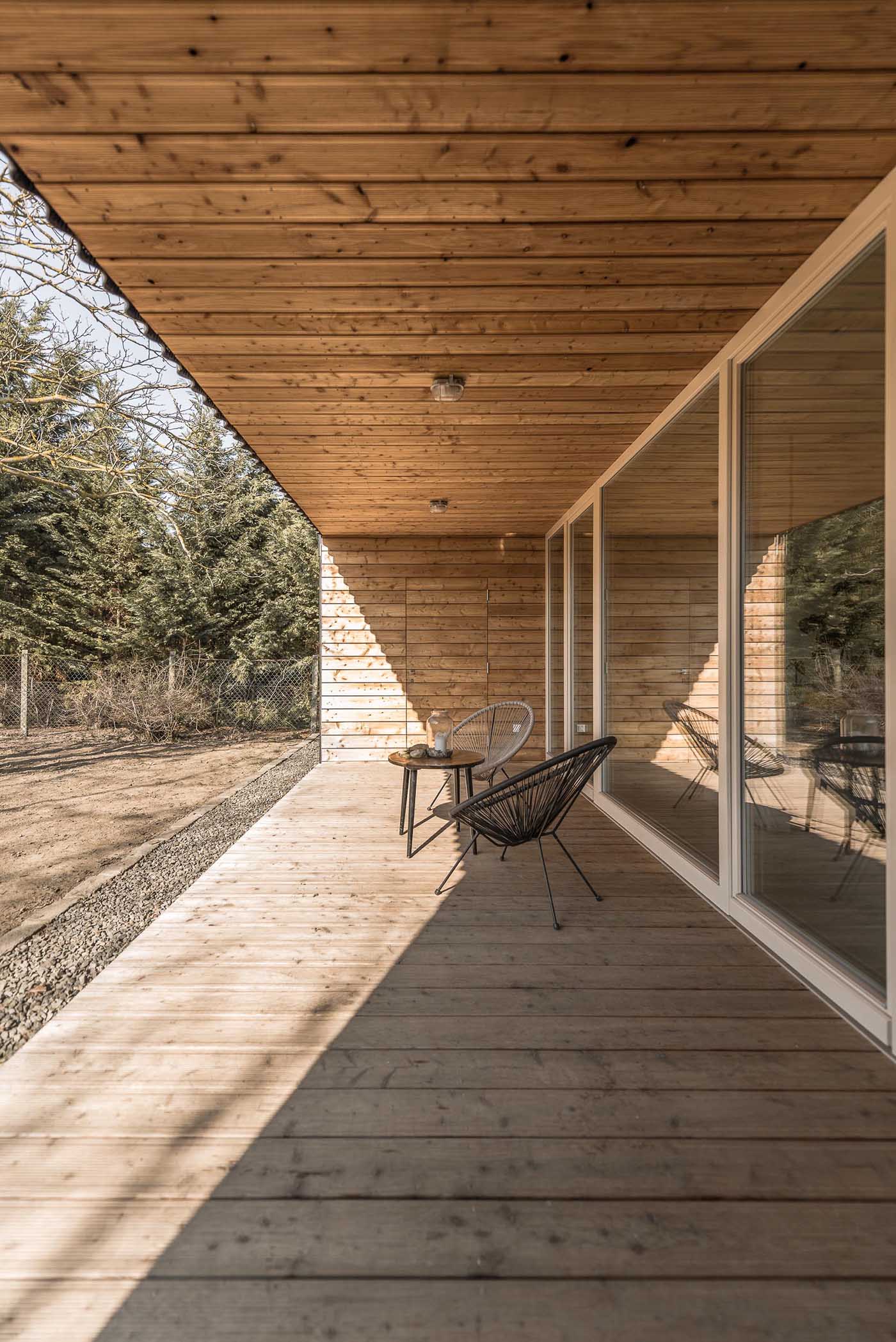 A modern black house with corrugated fibre-cement slate siding and alcoves lined with larch wood siding.