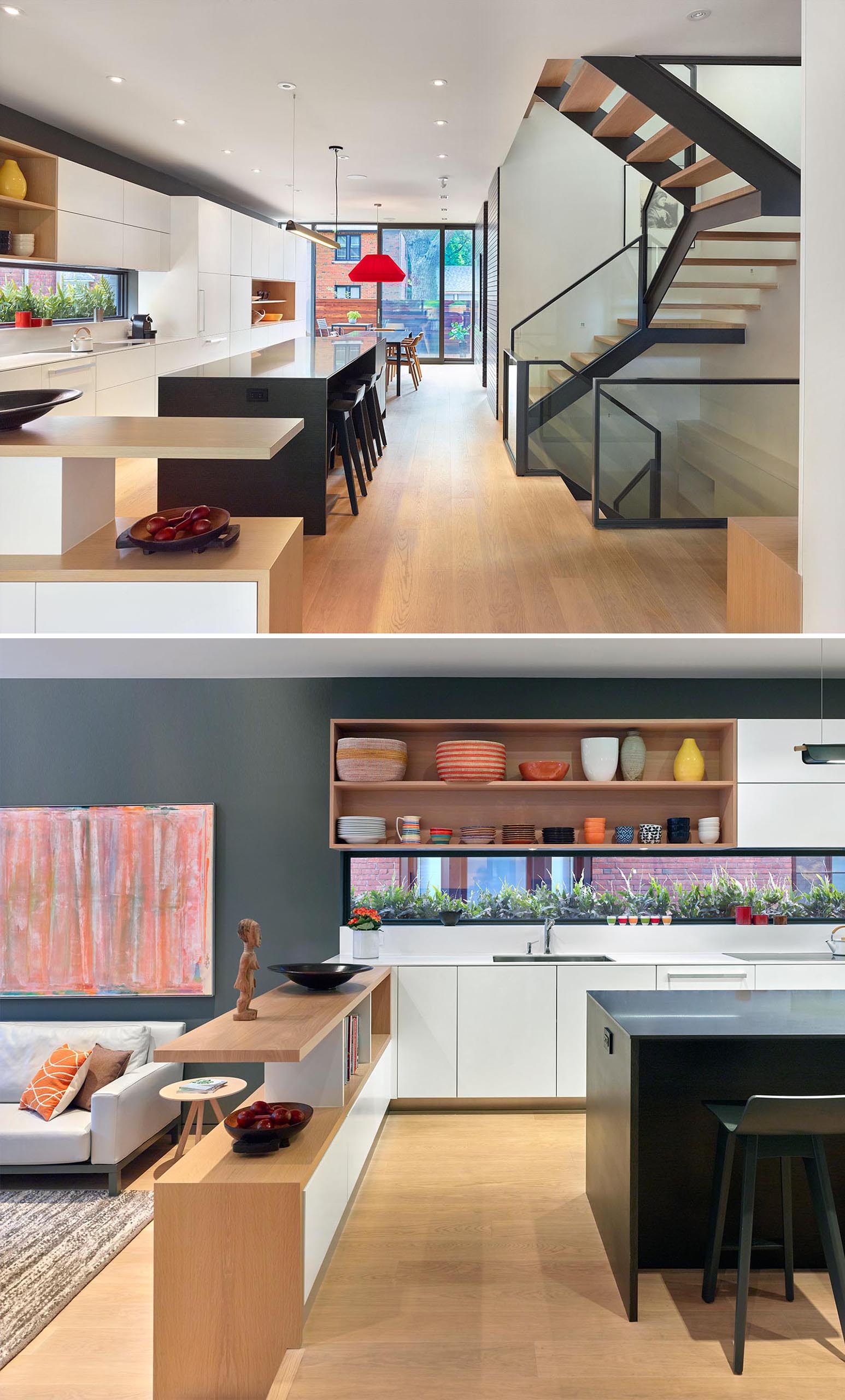 This modern kitchen has open wood shelves and a black island with room for seating, while a low shelf separates the kitchen and living room. A few steps lead down to the living room.