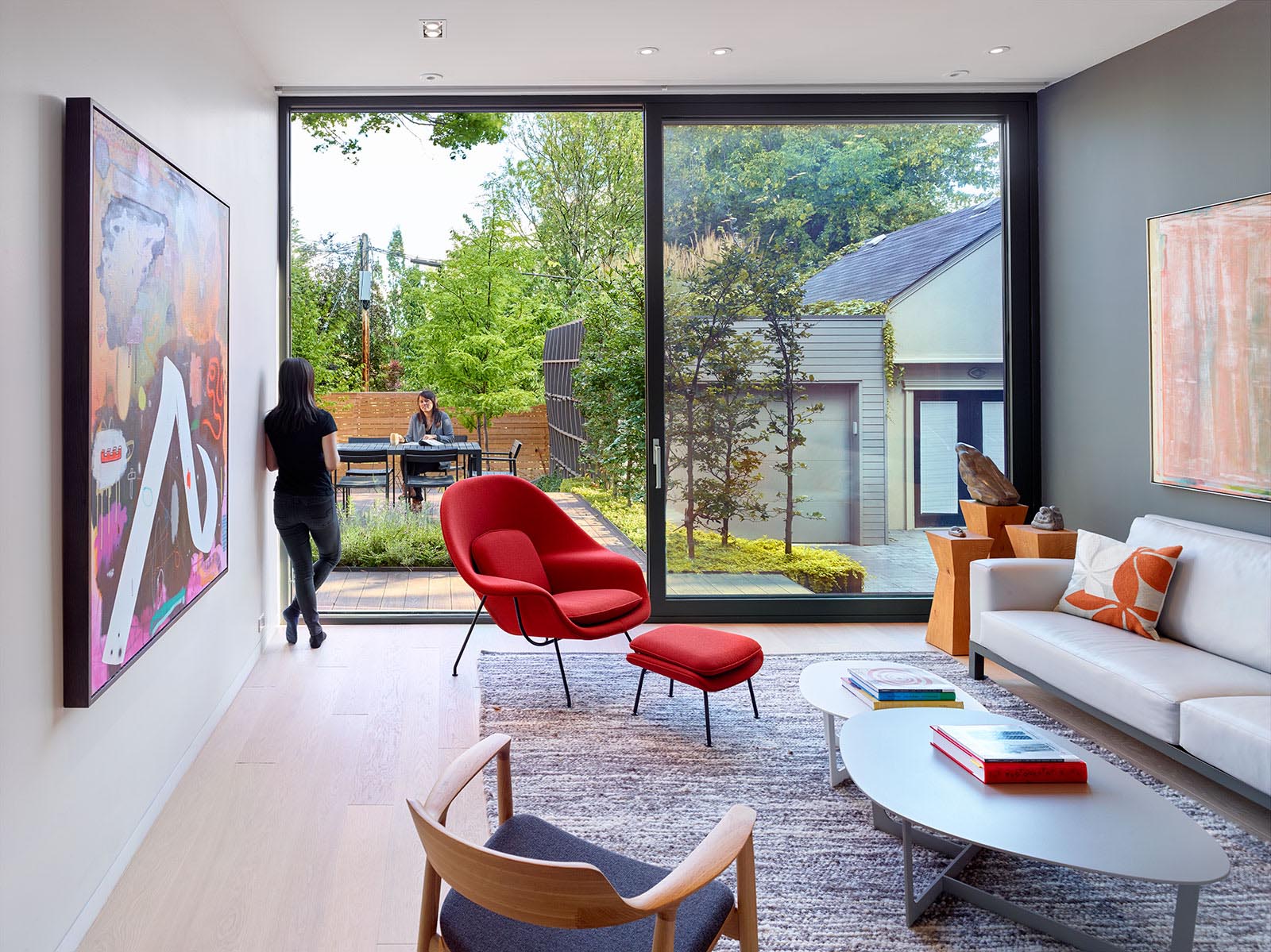 This modern living room, which has a dark accent wall, has an oversized sliding glass door that opens to a rear deck.