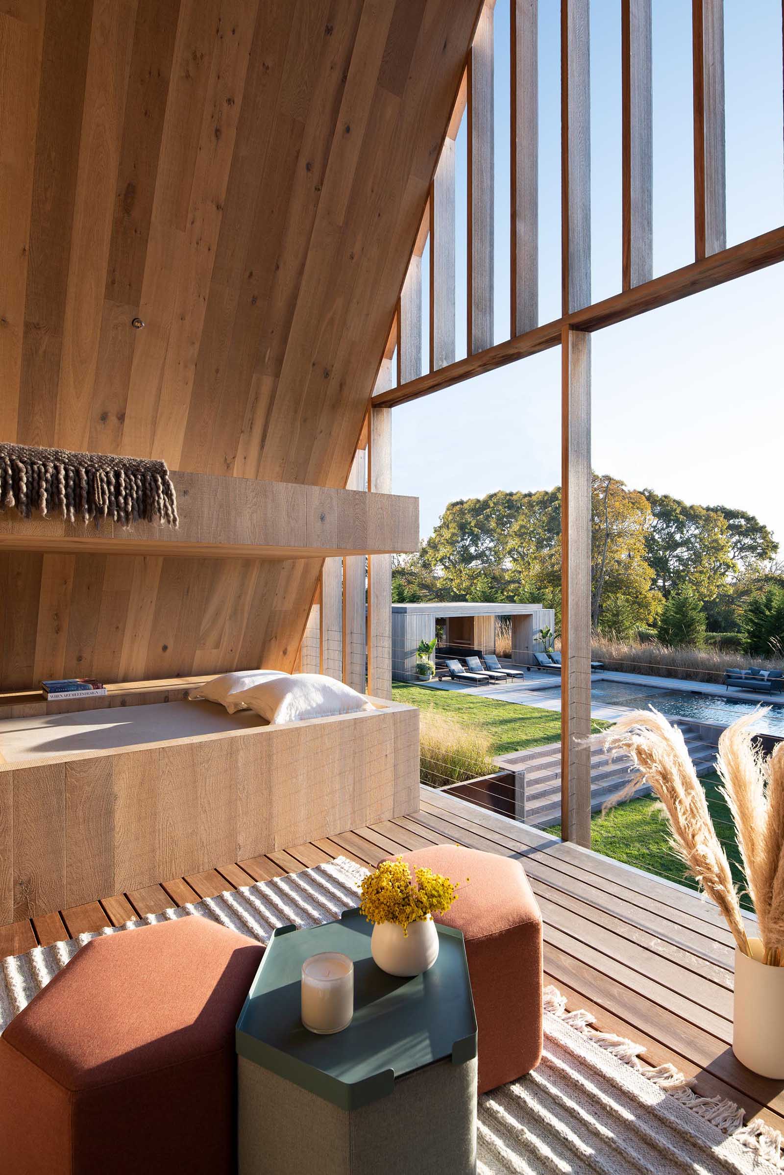 A covered outdoor space is dedicated to relaxing in the sunshine, with a built-in daybed that has views of the swimming pool.