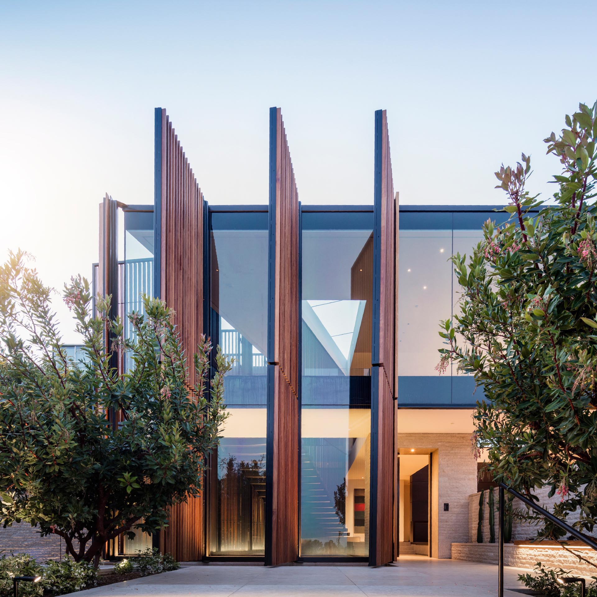 Oversized wood screens made from black metal and dark Ipe wood, offer the windows protection from the elements, security, and when open, allow natural light to flood the interior.