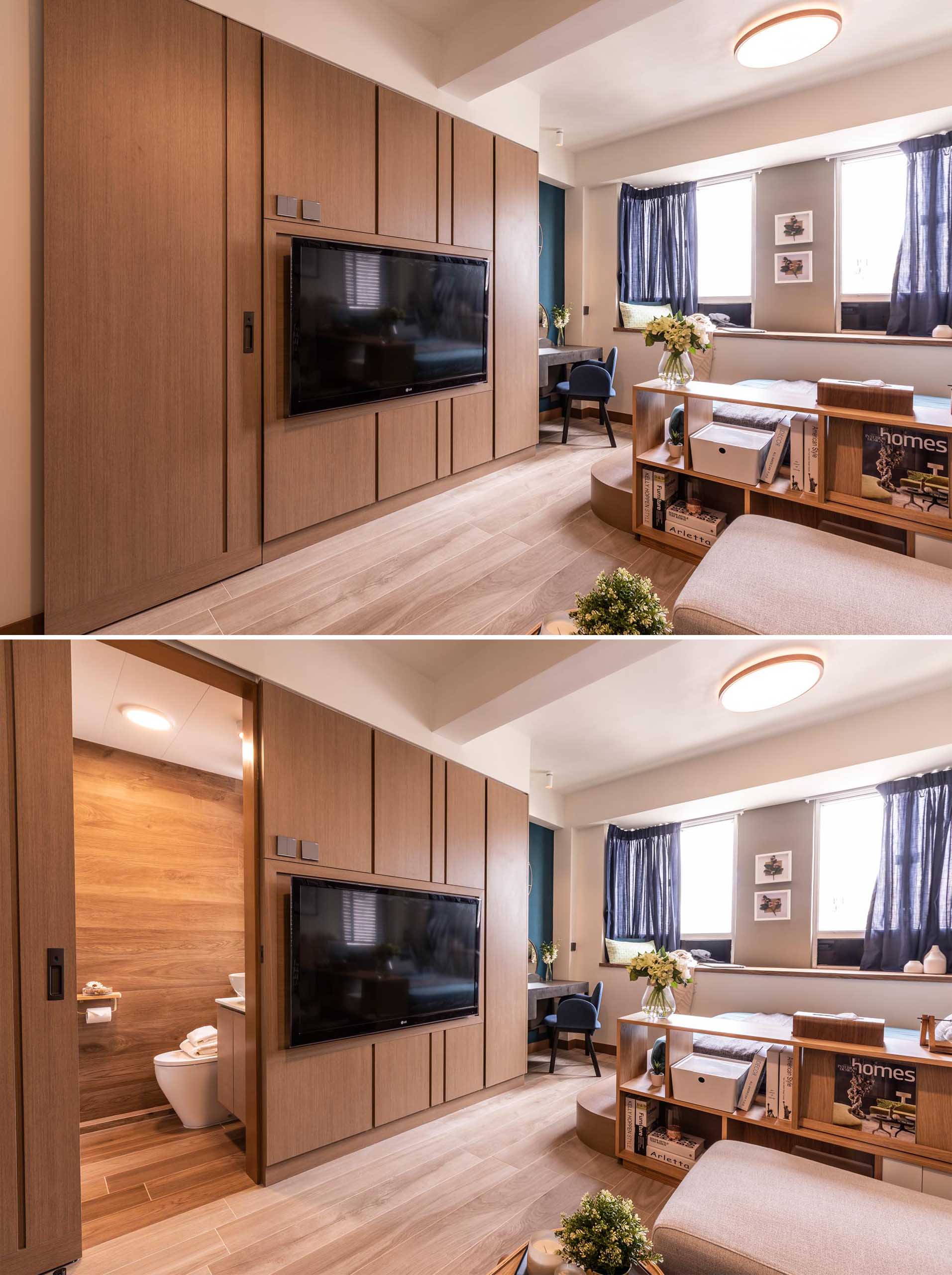 A small and modern apartment with a platform bed, a tiny kitchen, and a wood feature wall that hides a wardrobe, bathroom door, and structural column.