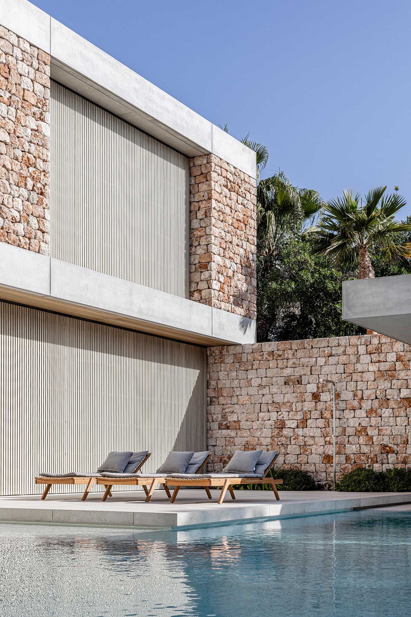 A modern stone house with an infinity edge swimming pool.