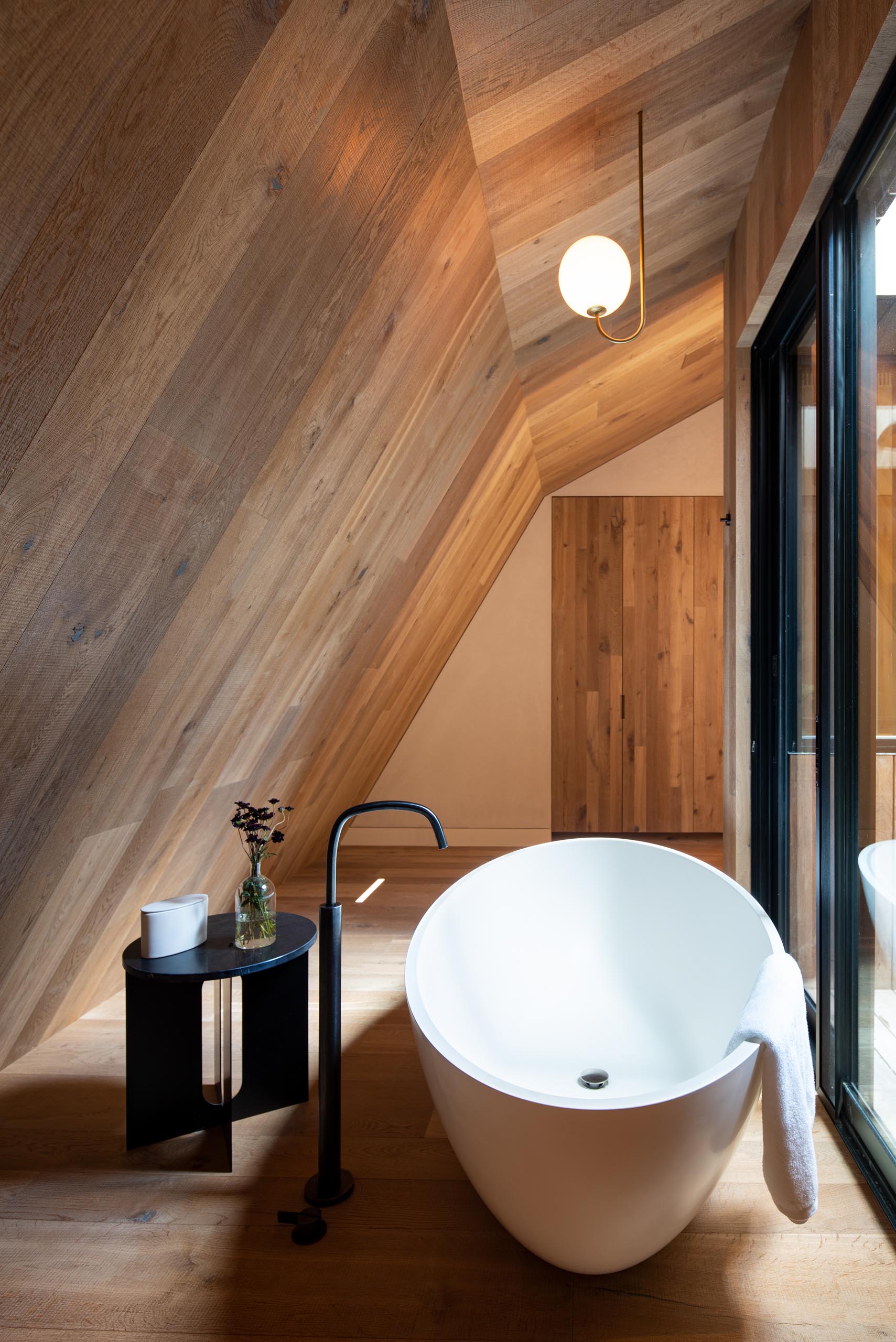 A modern wood lined bathroom with a freestanding bathtub.