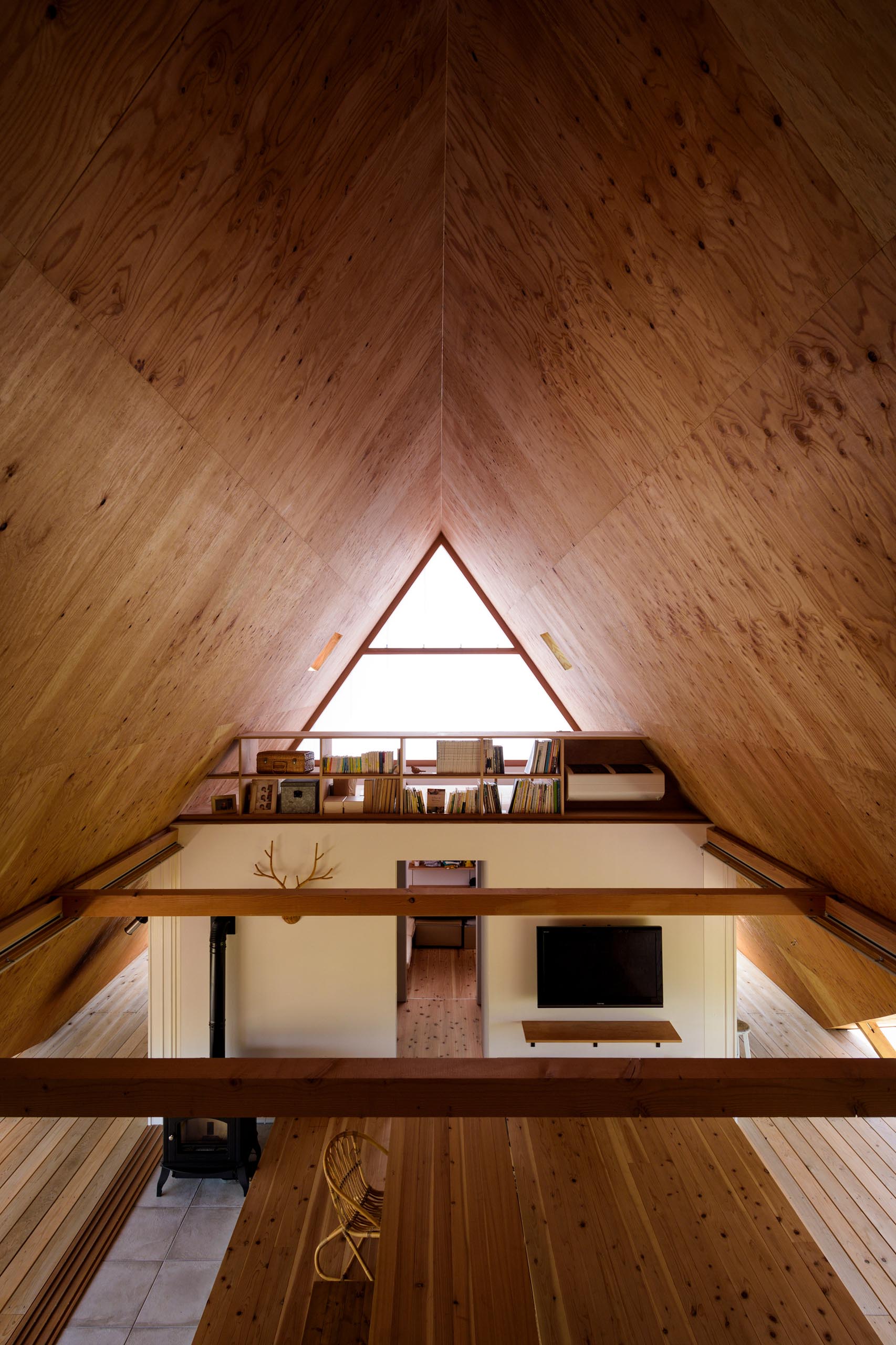 The wood-lined interior of this modern A-frame house has had its storage, partitions, and private rooms removed as much as possible in order to simulate one large open space that adapts to the user’s needs.