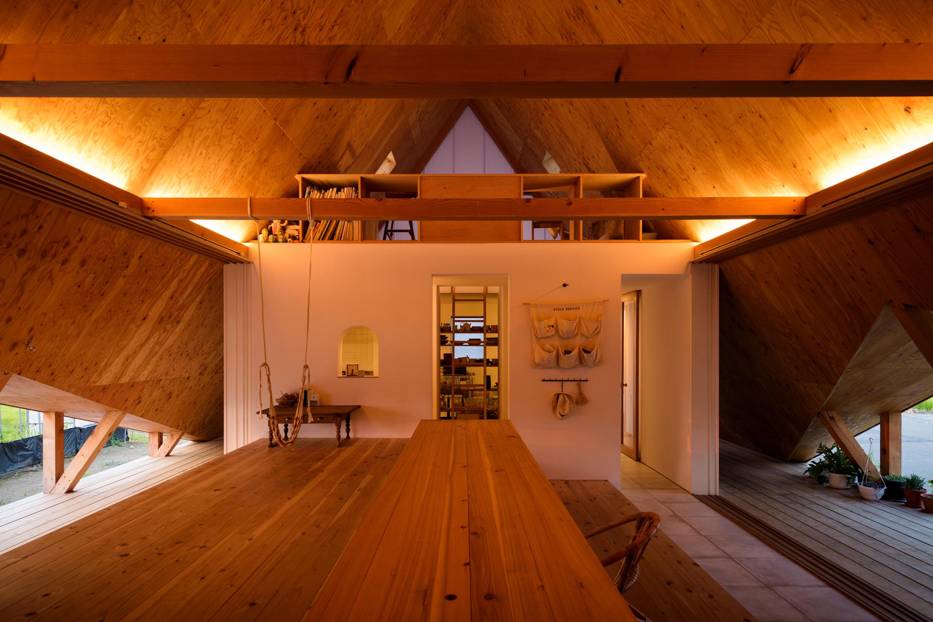 At night, hidden lighting adds a warm glow to the interior of this modern a-frame house and highlights the angled ceiling design.