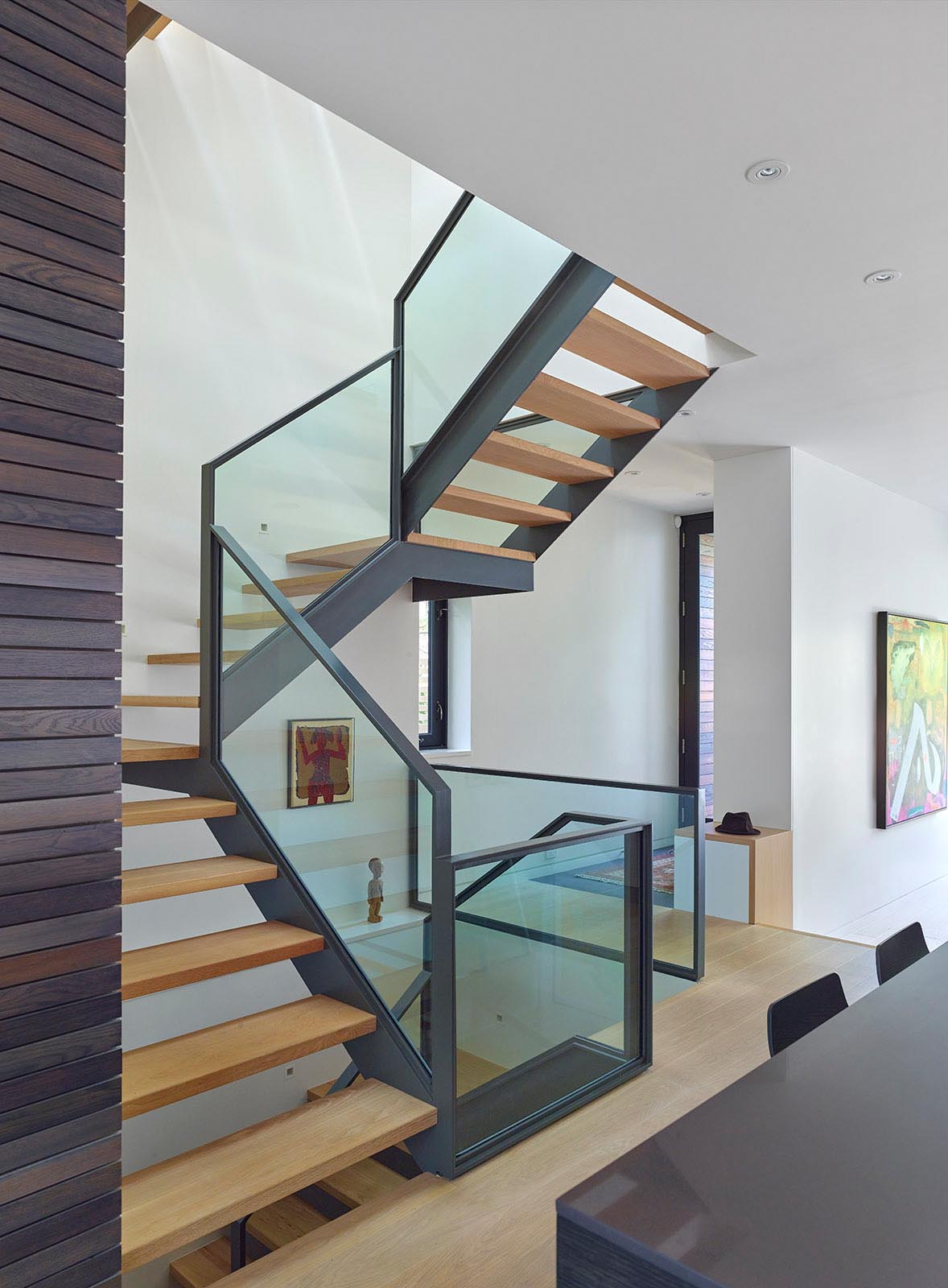 Steel and wood stairs with glass railings connect the various levels of this modern home.