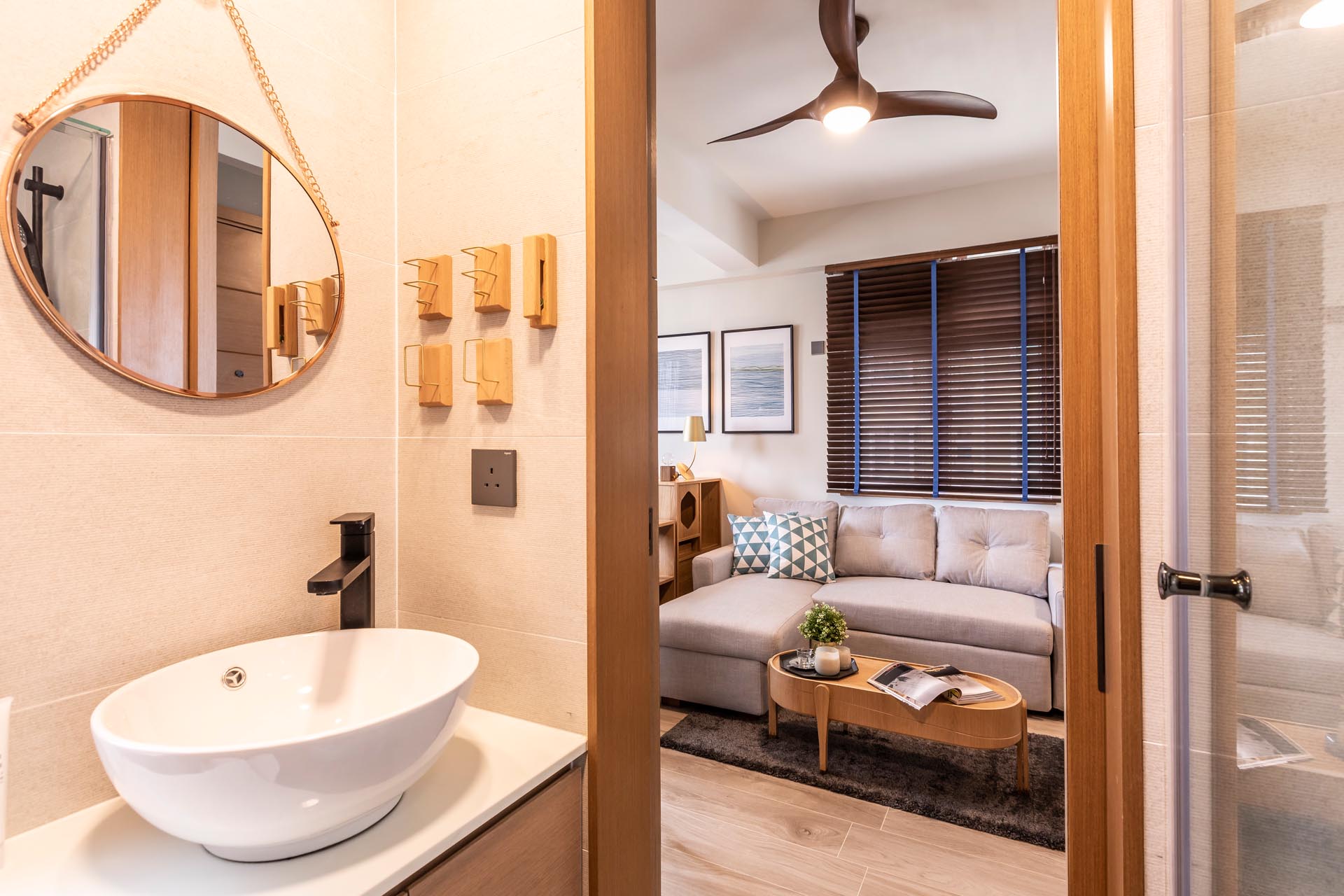 This modern bathroom in a small apartment includes a wood accent wall and a glass-enclosed shower.