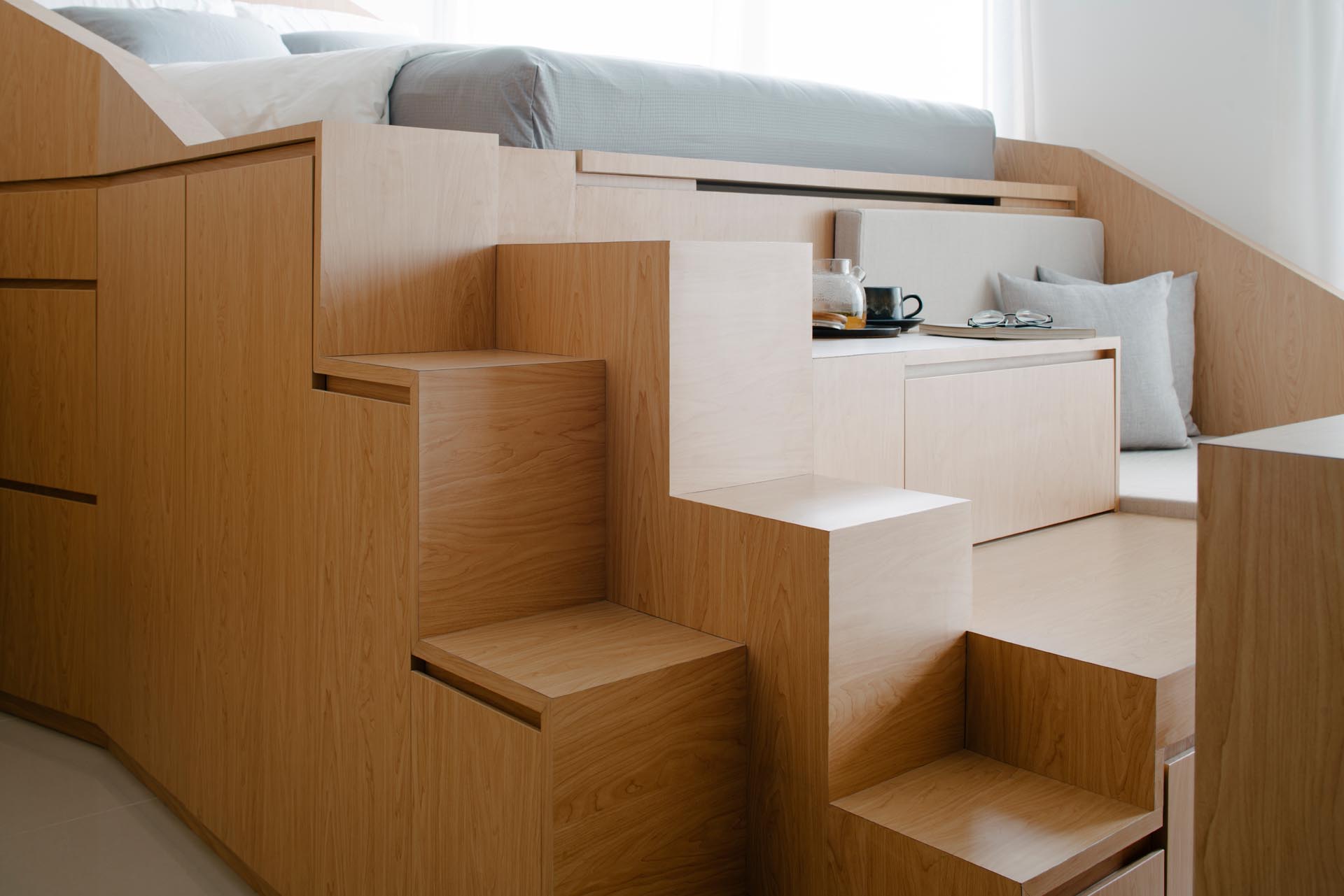 A custom design loft bed with a sofa and storage, has integrated steps up to the bed.