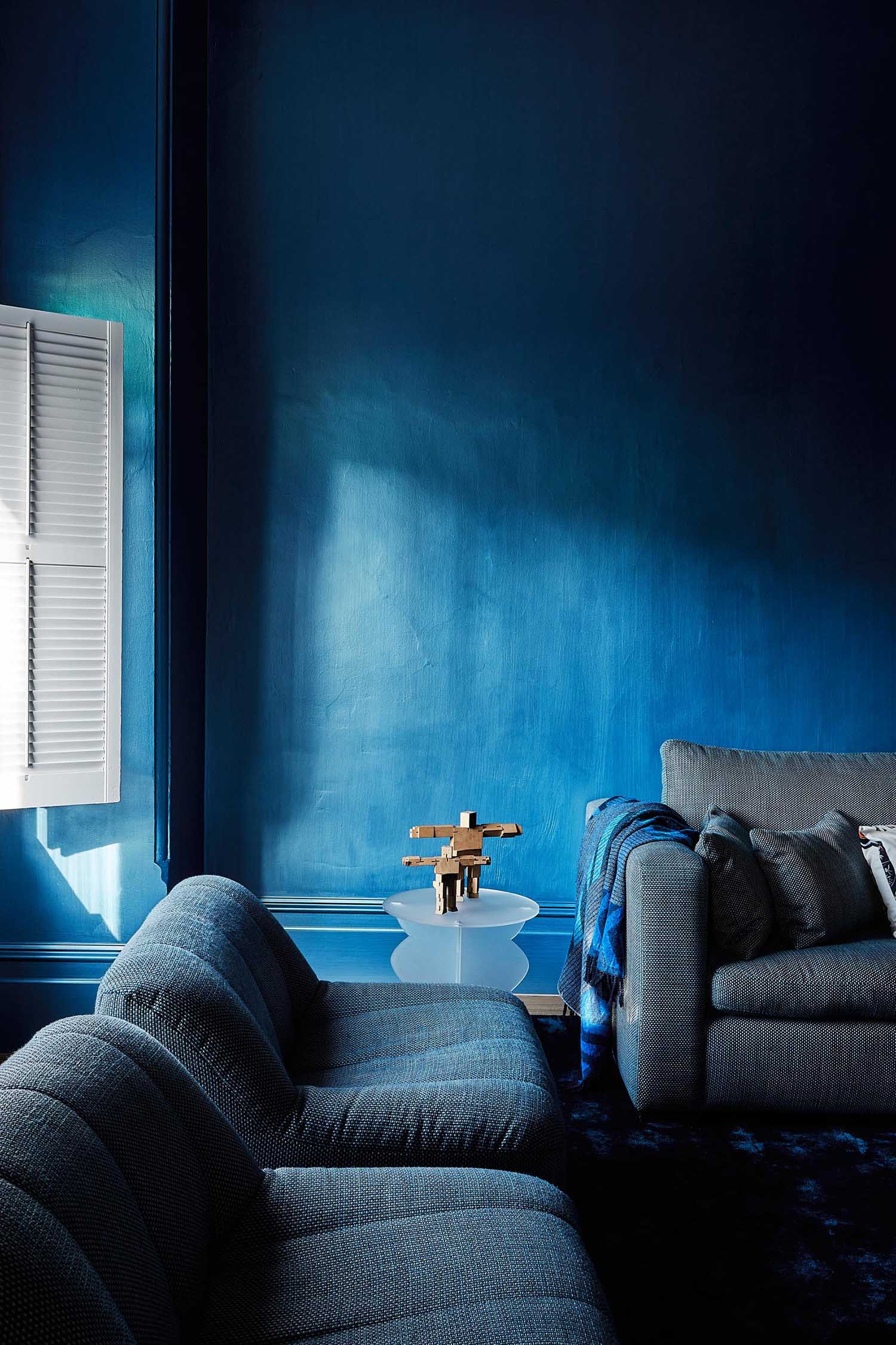 An updated living room in a heritage house has a bold blue color palette.