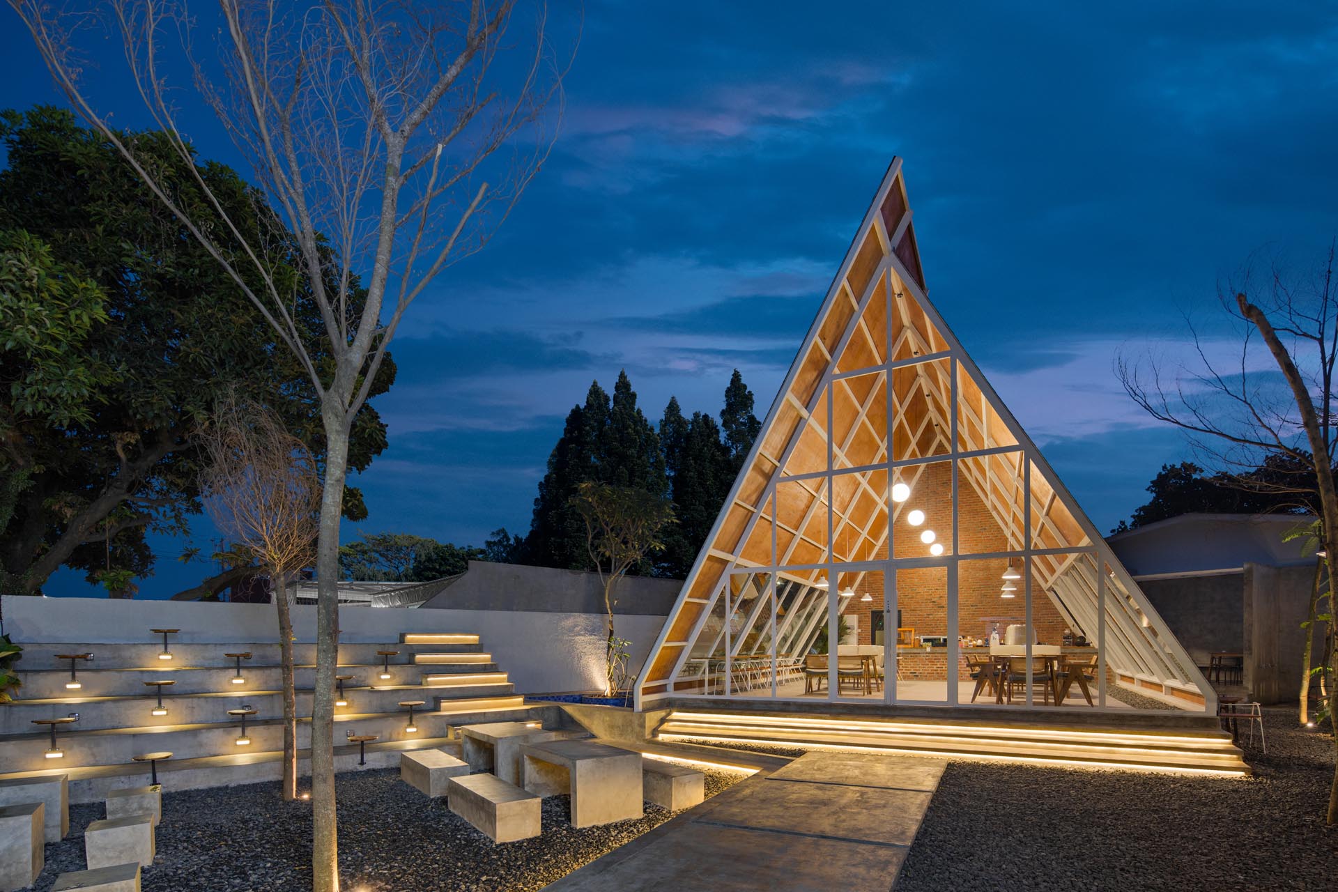 A modern A-frame coffee shop design with an exposed structure, a wall of windows, and wood detailing.