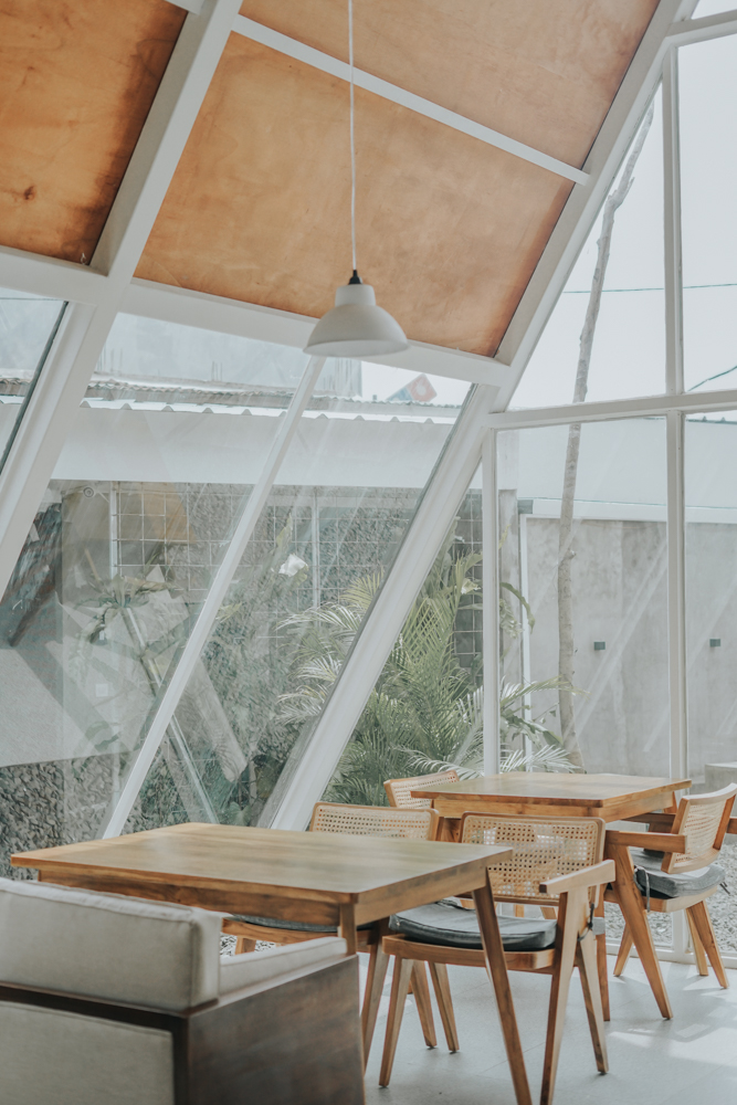 A modern A-frame coffee shop design with an exposed structure, a wall of windows, and wood detailing.