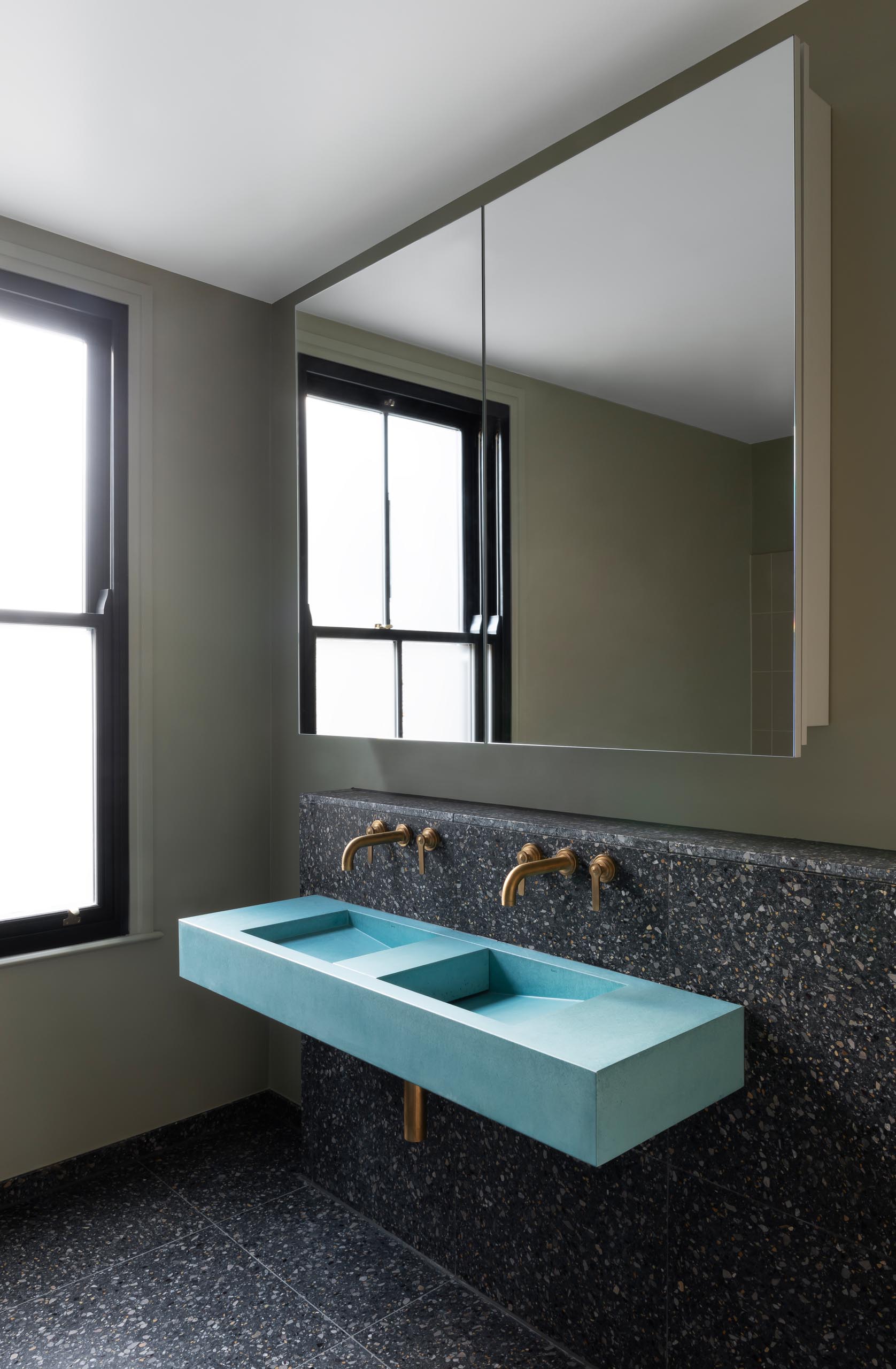 A modern bathroom with Terrazzo and gold accents, and a blue sink.