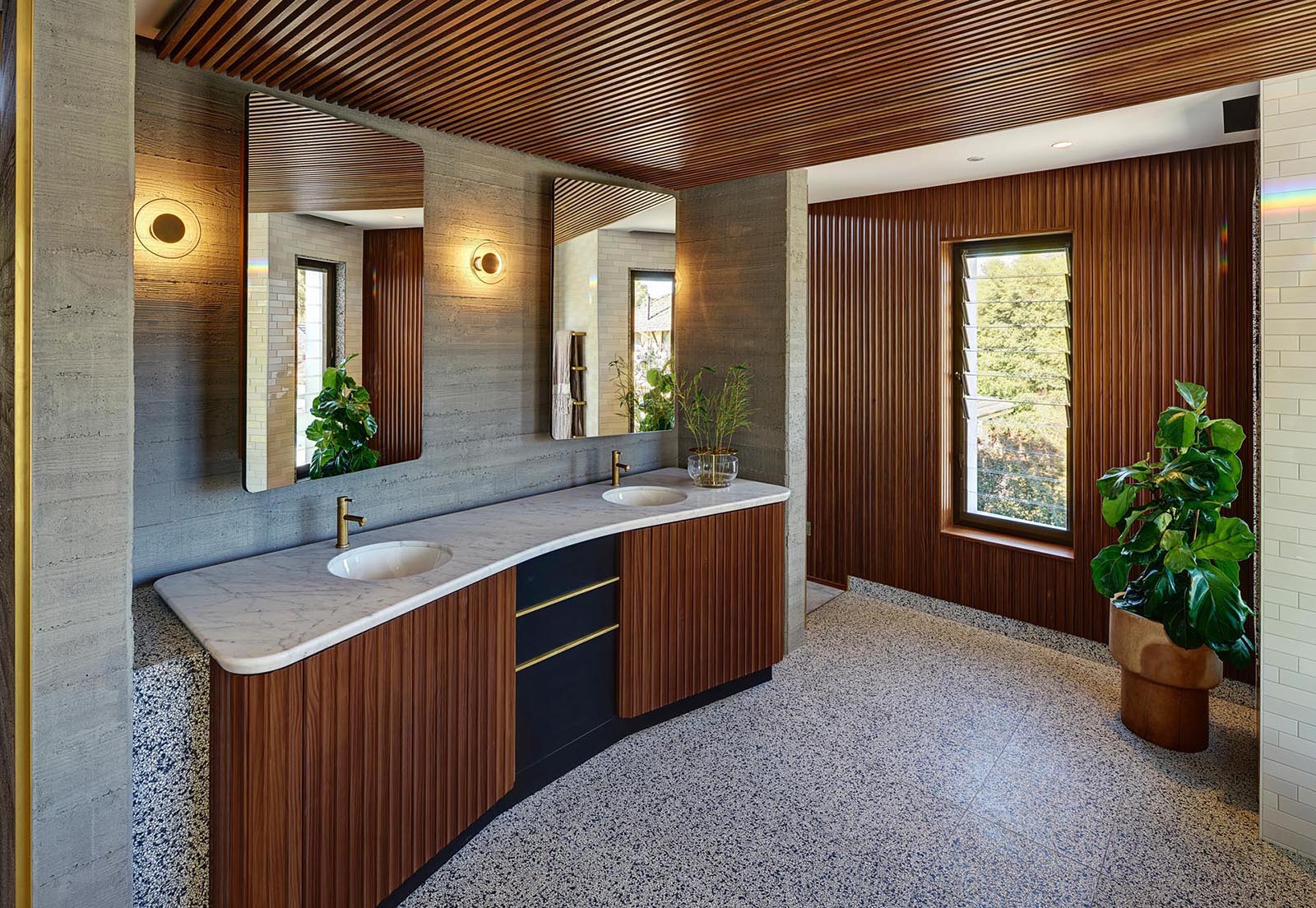 This modern master en-suite bathroom features wood to provide a sense of warmth to the space, while the mirrors open to reveal shelving.