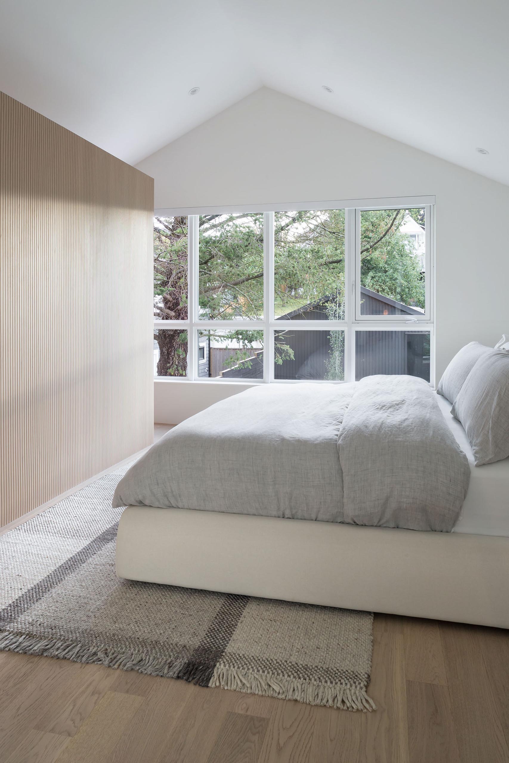In this modern bedroom, the white walls and ceiling have been kept minimal, while a wood partition wall separates the closet from the sleeping area.