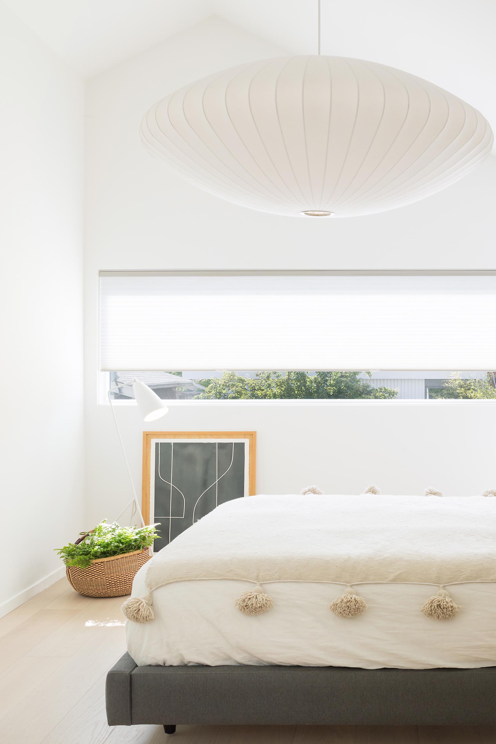 In this modern bedroom, there's a horizontal window that adds natural light to the room.