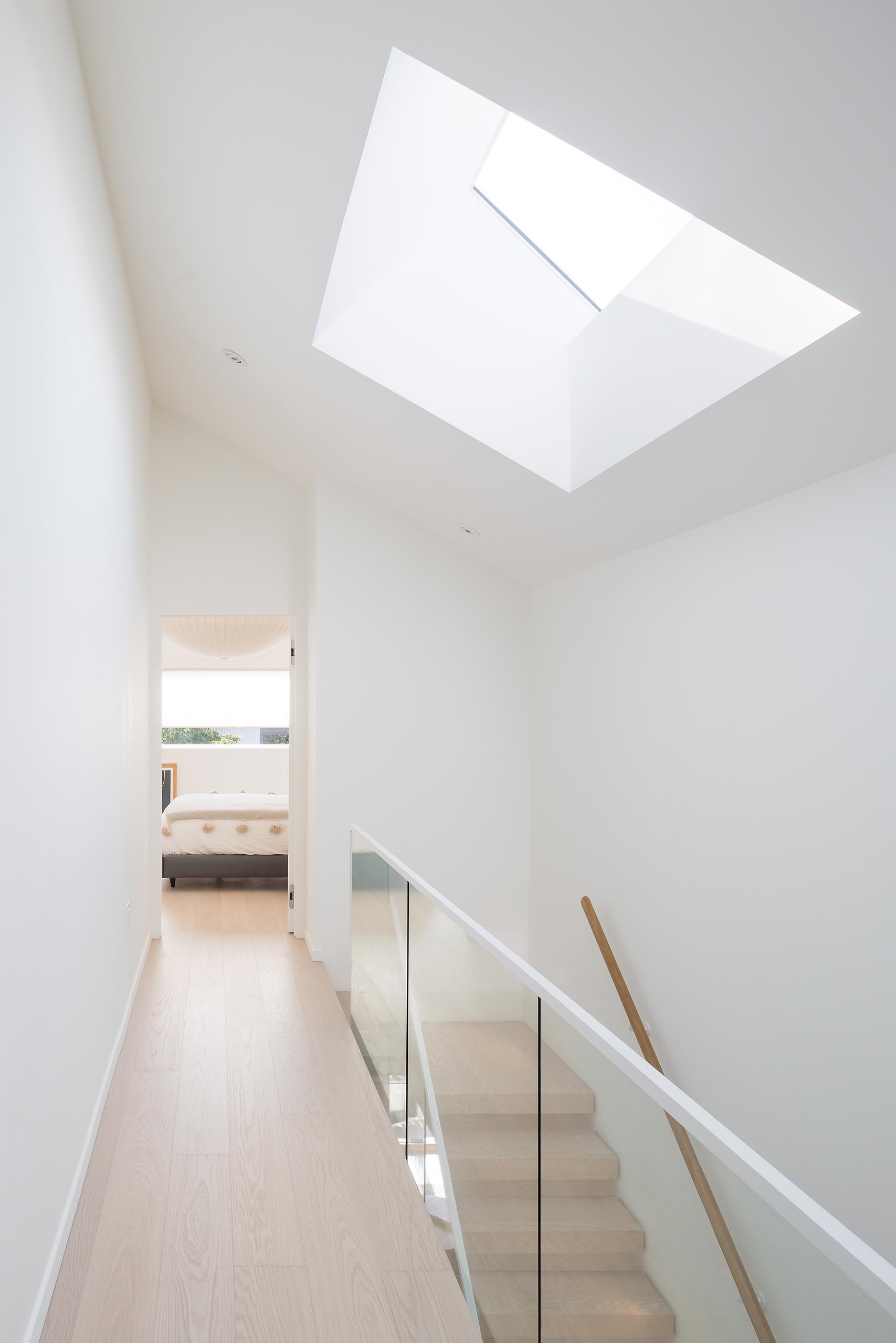 At the top of the stairs in the modern home, there's a hallway with vaulted ceilings and a skylight.