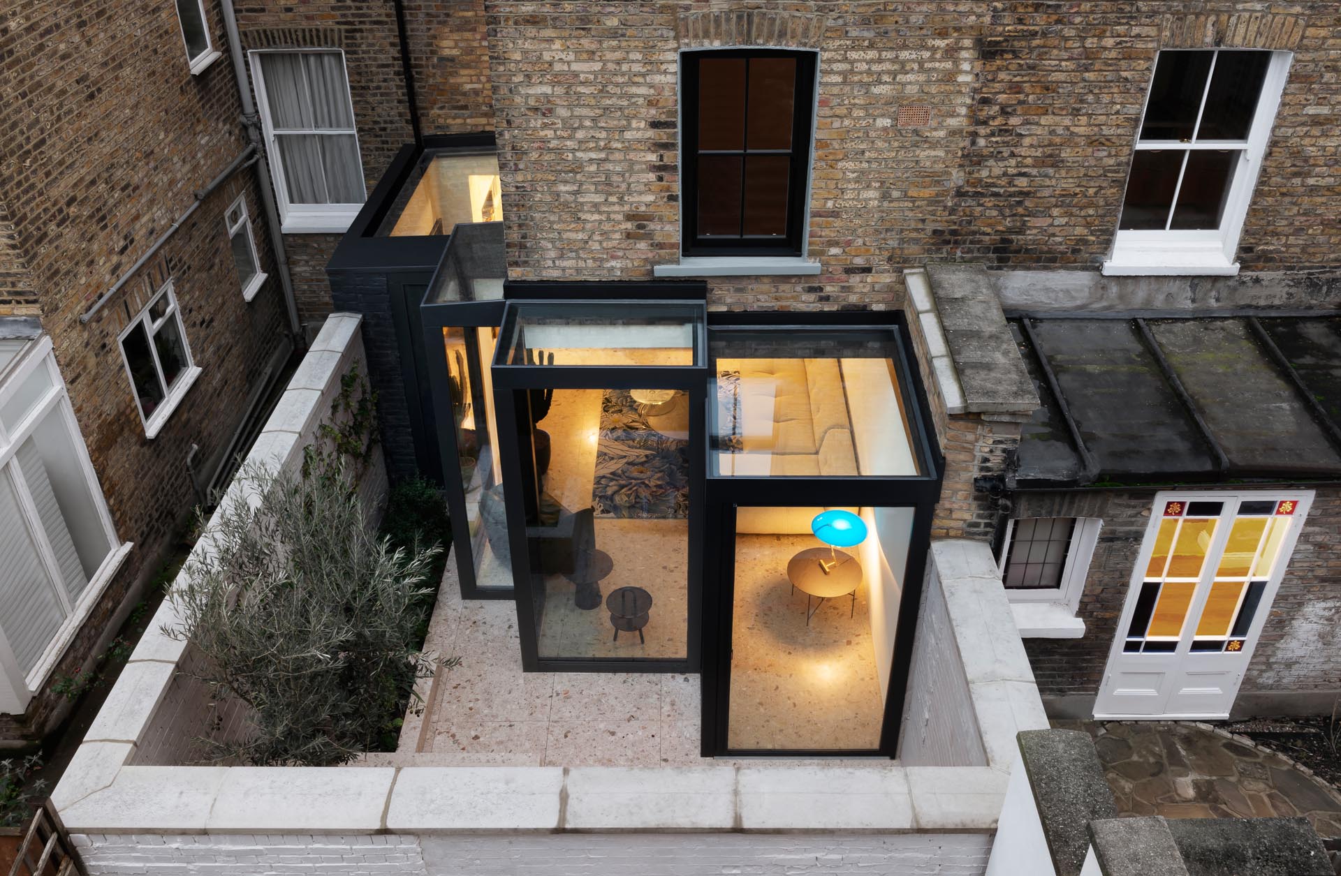 This modern rear extension has steel-frame construction, similar to that of a museum case, with thick black frames that surround glass volumes.