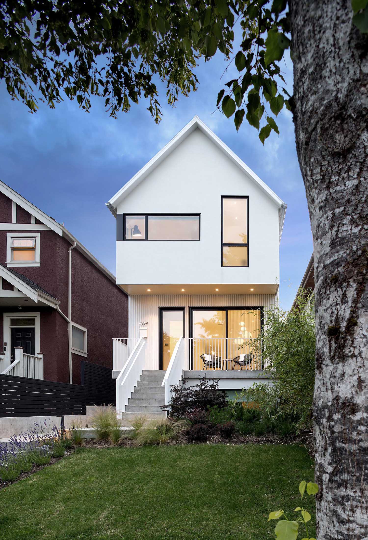 This modern home is clad in a white painted smooth stucco with a metal standing seam roof.