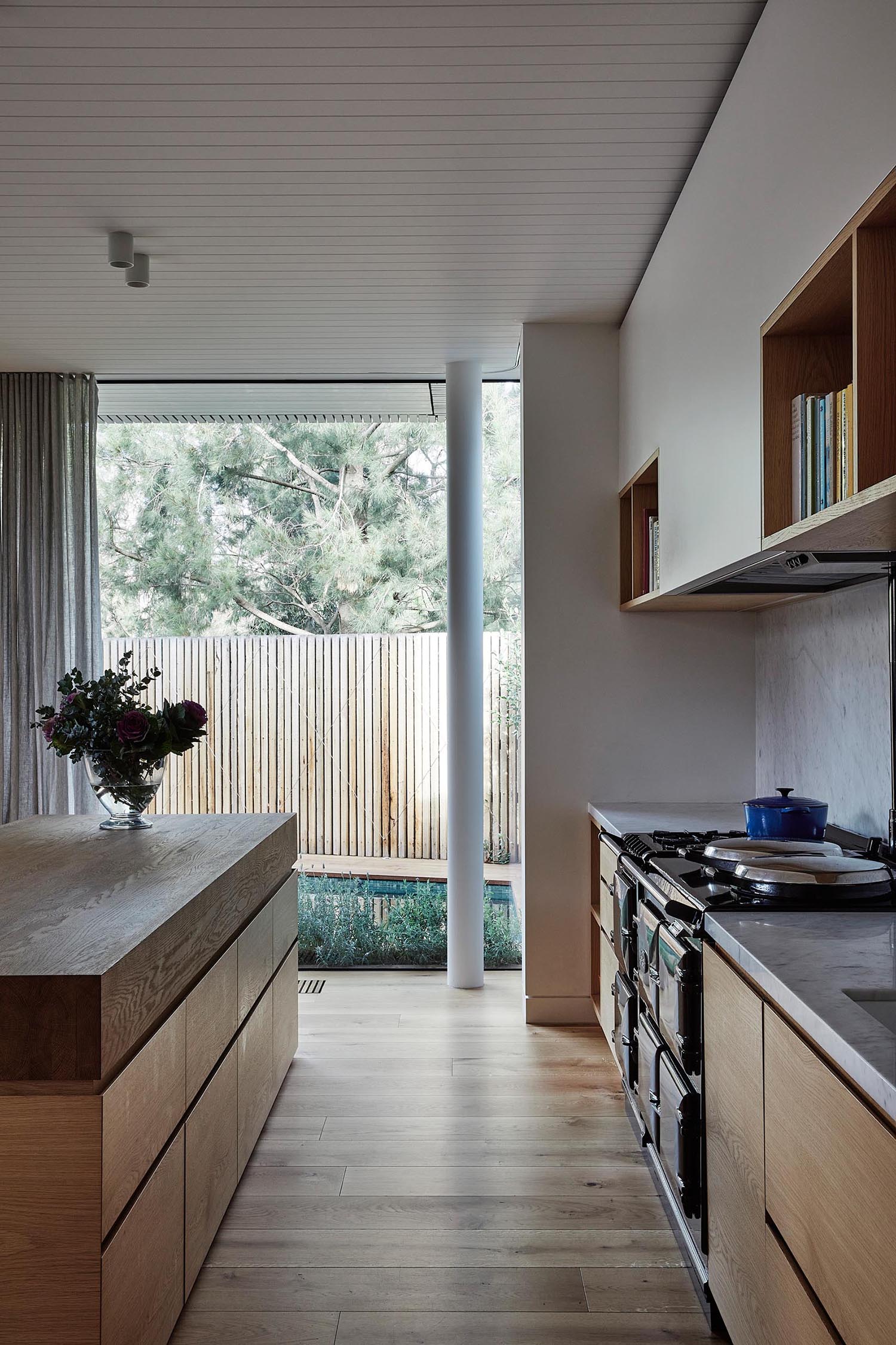 A modern kitchen with an island that has a very thick butcher block countertop.