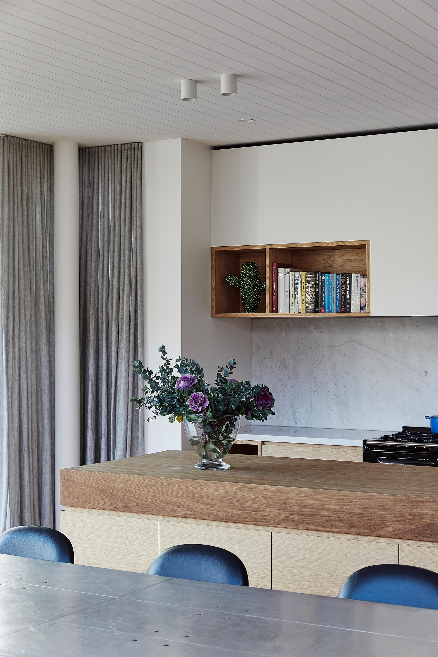 A modern kitchen with an island that has a very thick butcher block countertop.