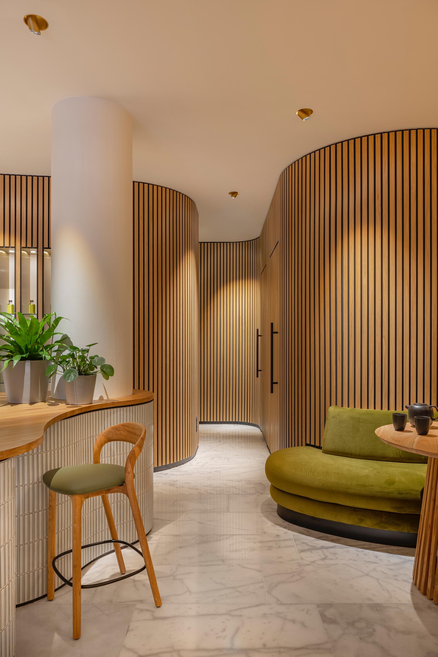 Blending into the organically shaped walls are the doors to the massage rooms, only noticeable by the black hardware.