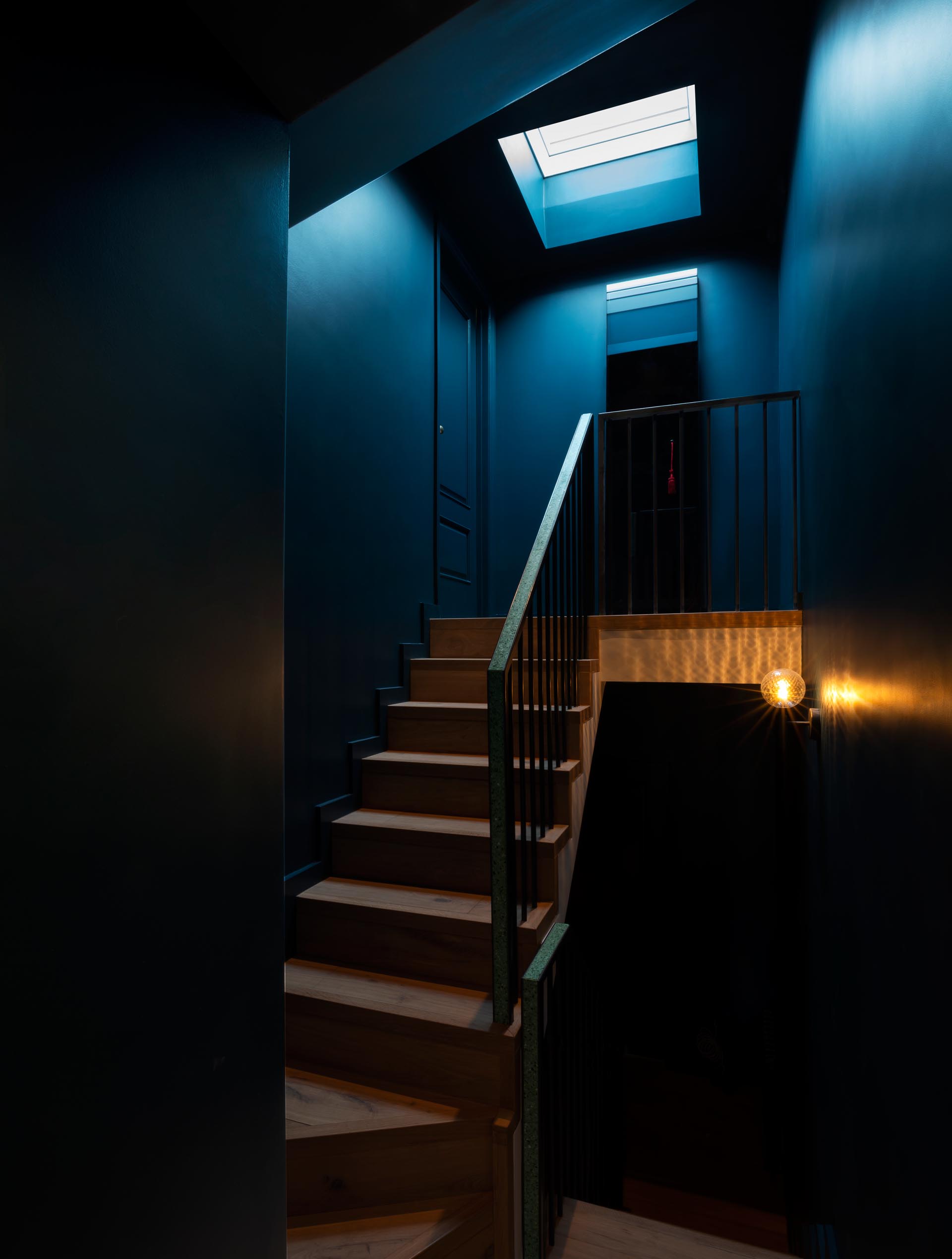 A dark and dramatic staircase with a custom-designed handrail that includes a Terrazzo accent.