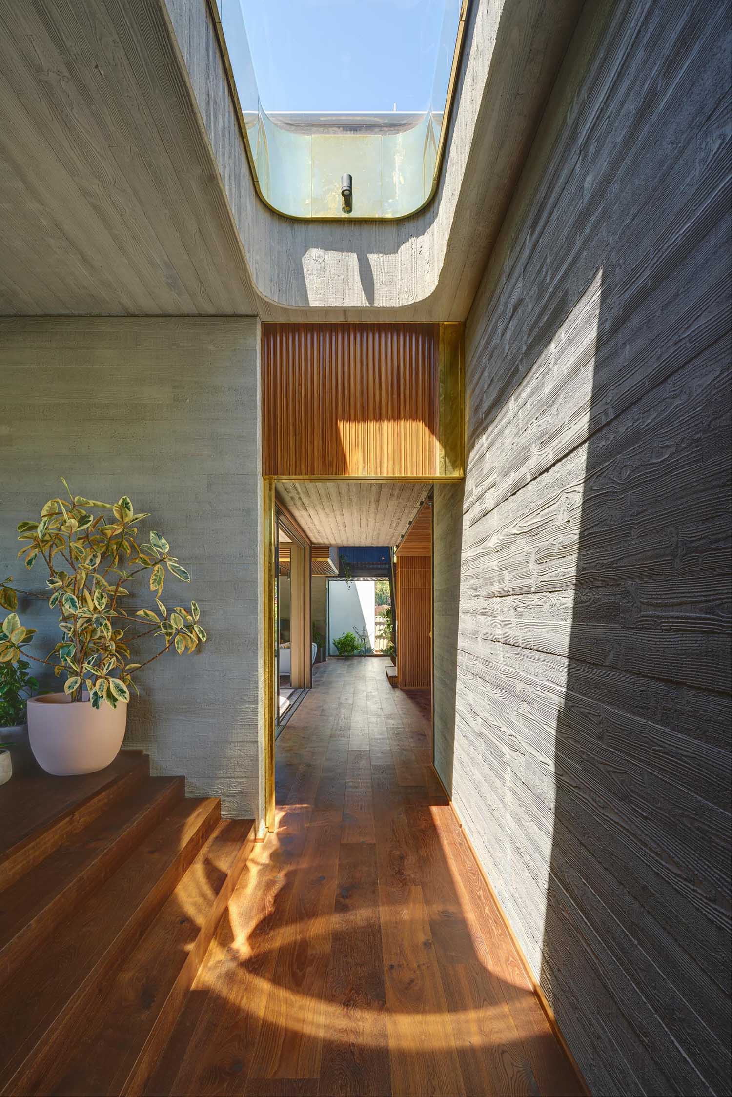 A modern home with wood and brass detailing and board-formed concrete walls.