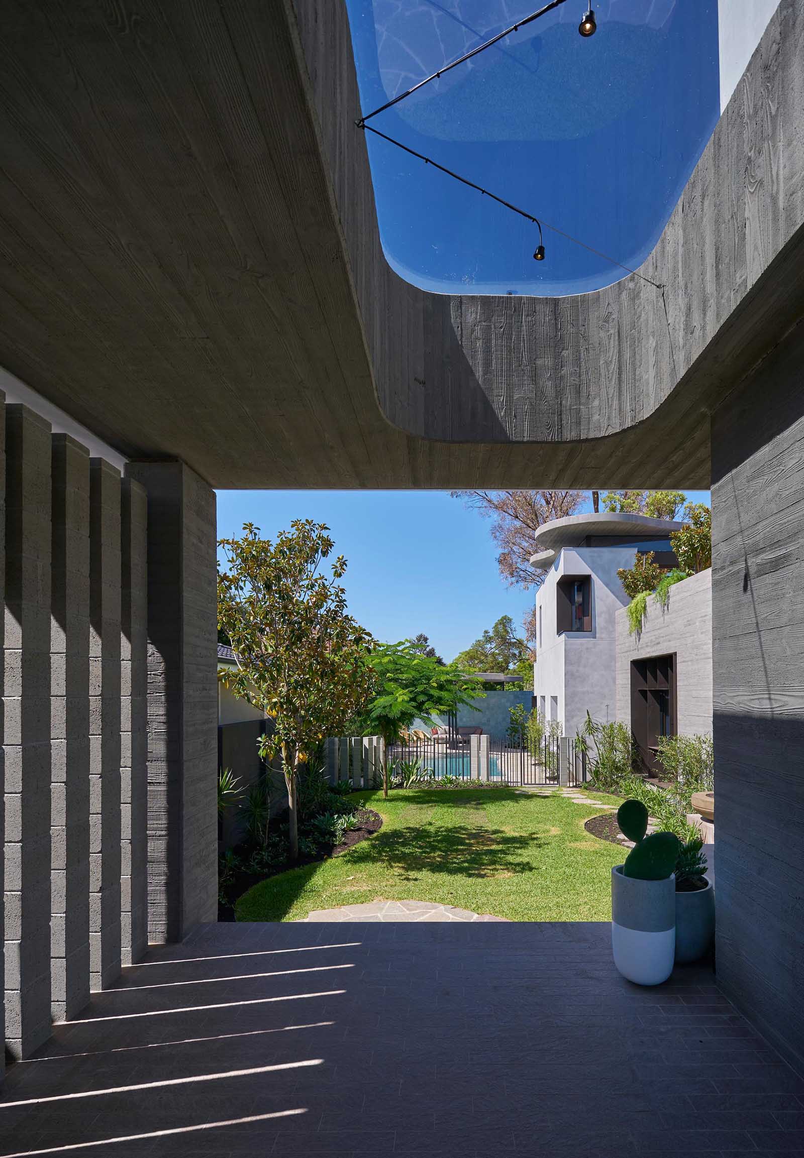A modern house board formed concrete walls and an organically shaped yard that provides access to a swimming pool.