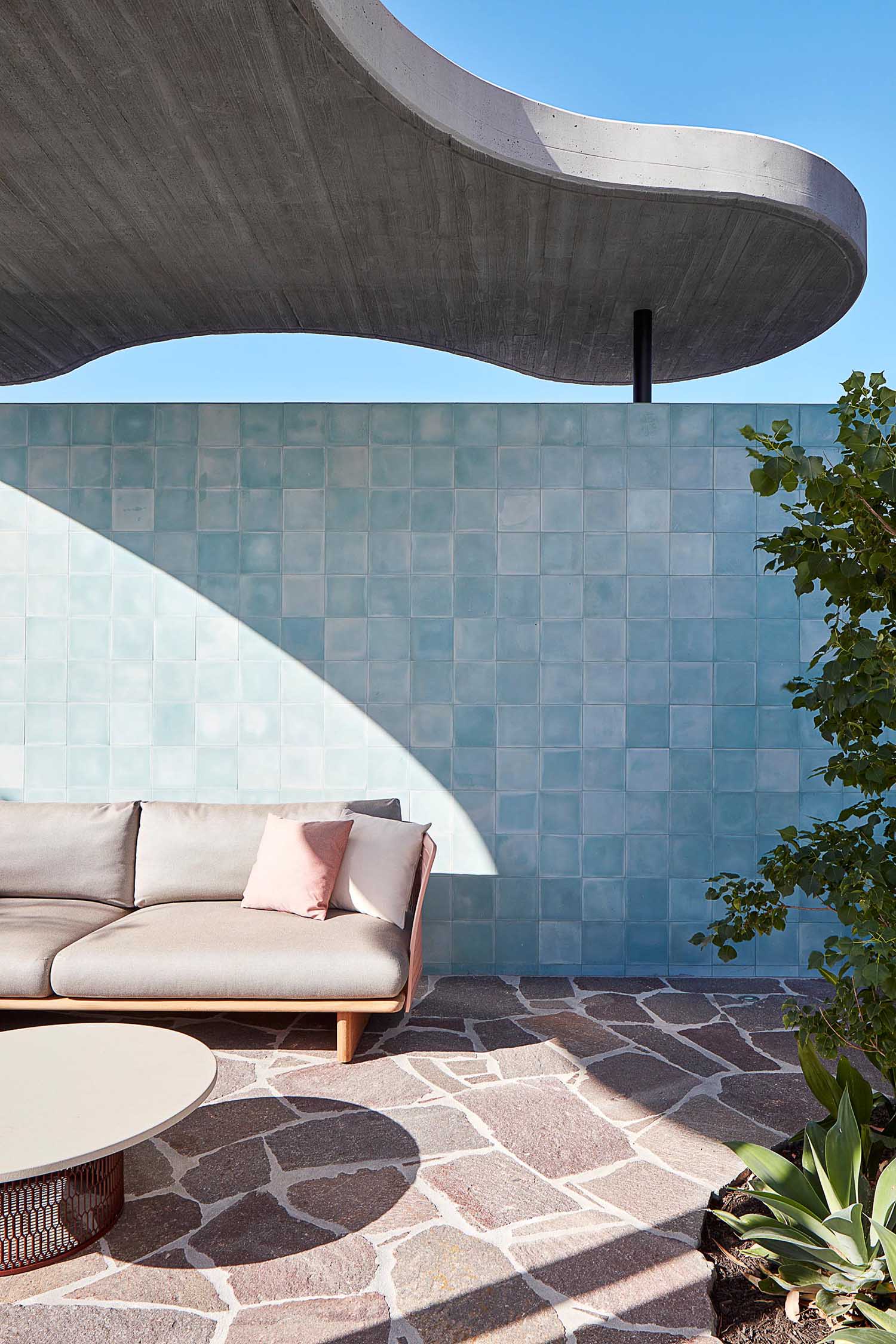 A modern patio with blue tiles and a pink couch.
