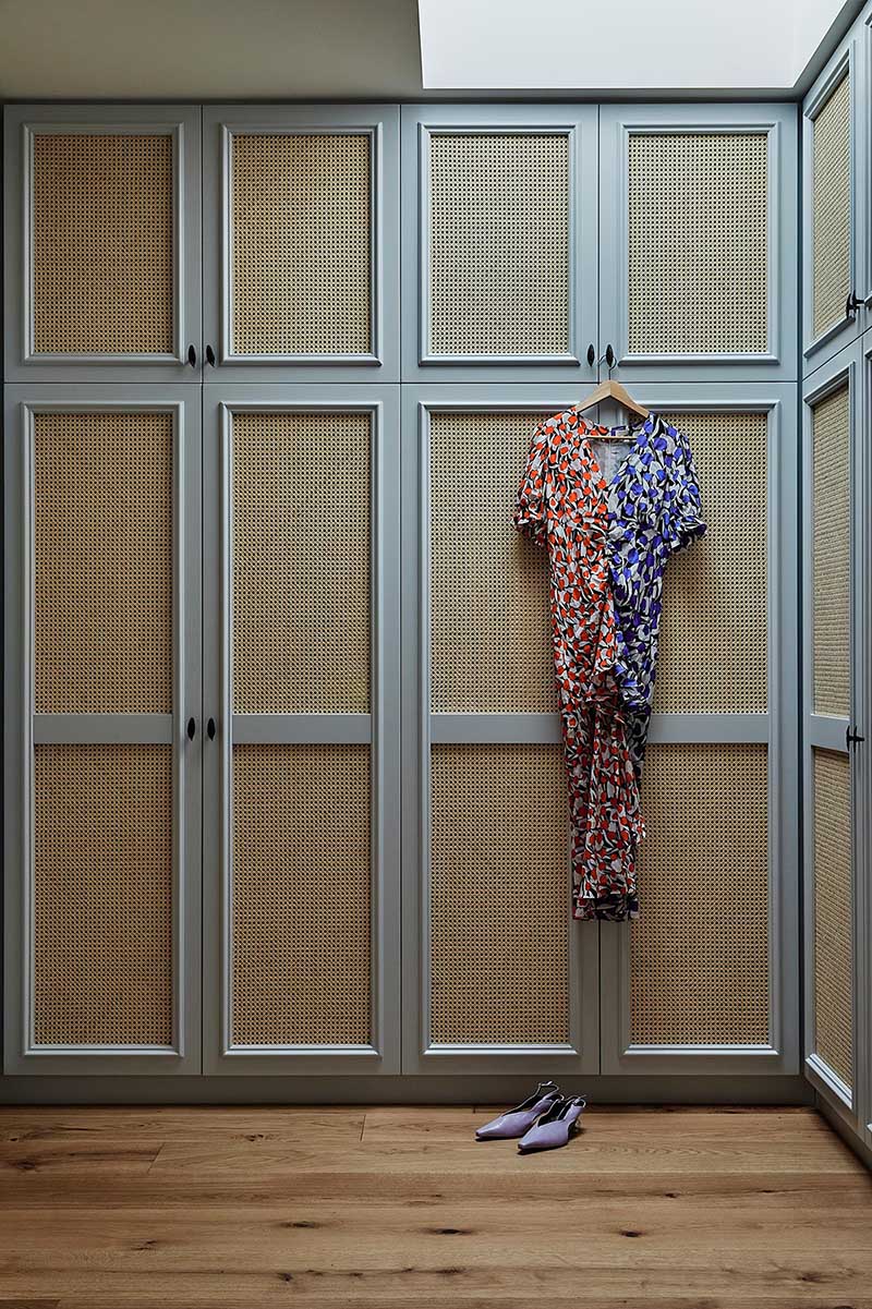 A walk-in closet with custom cabinetry and woven fronts.