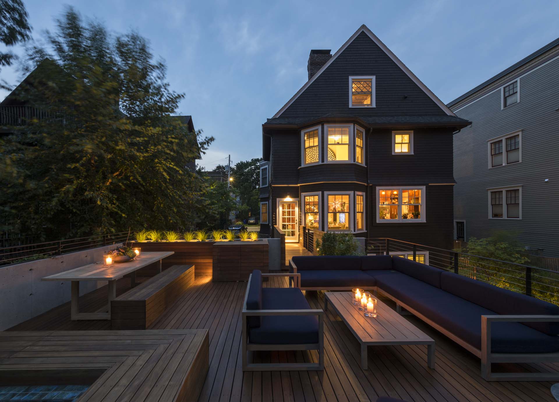 A rooftop deck on a garage is connected to the house via a small bridge.