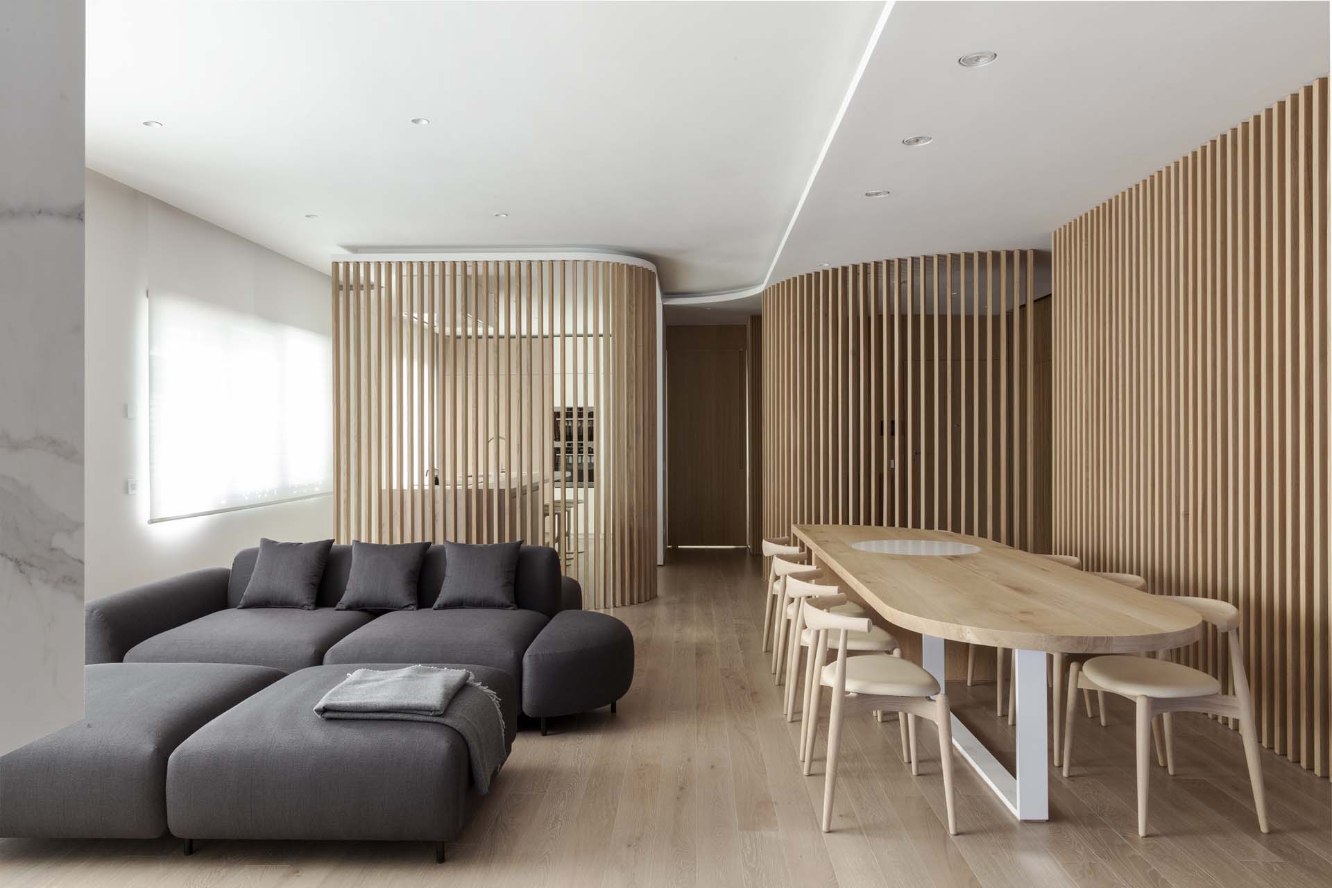 A modern apartment interior uses curved oak partitions to create zones.
