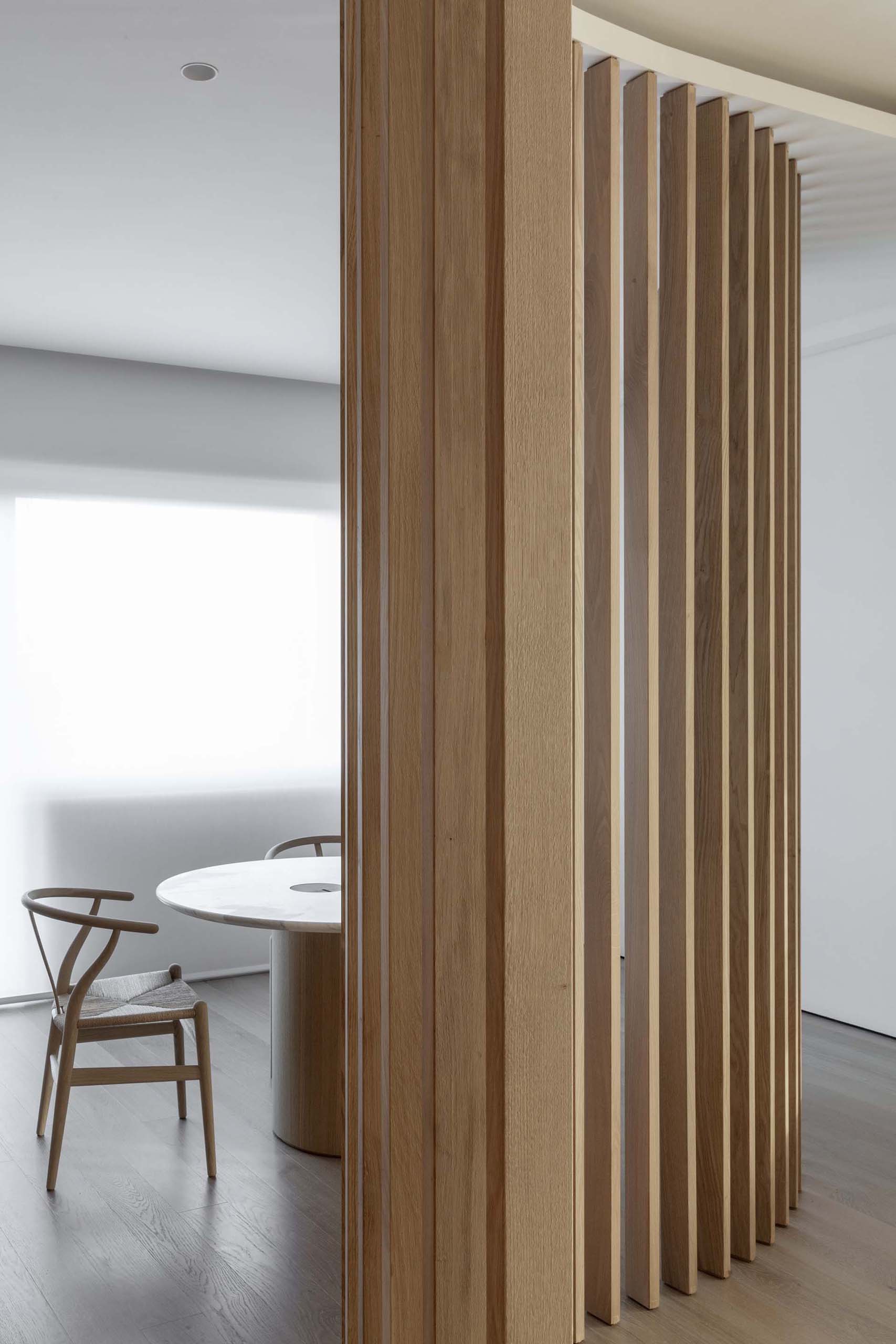 An curved oak slat partition separates the study from the living room.