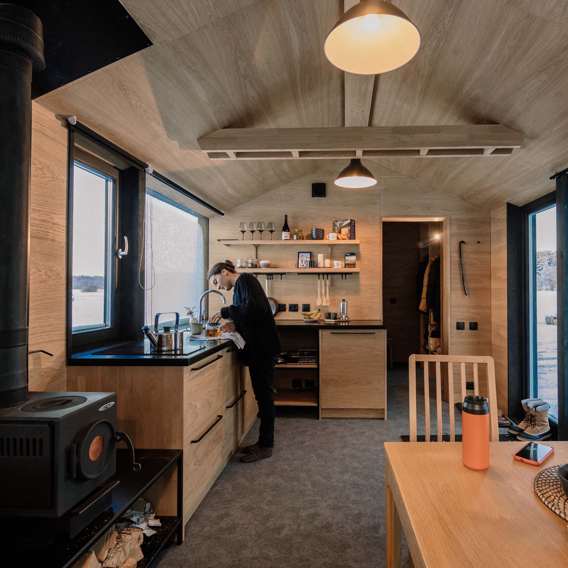 In the kitchen of this modular home, the black countertop and hardware complements the nearby black fireplace and window frames. 