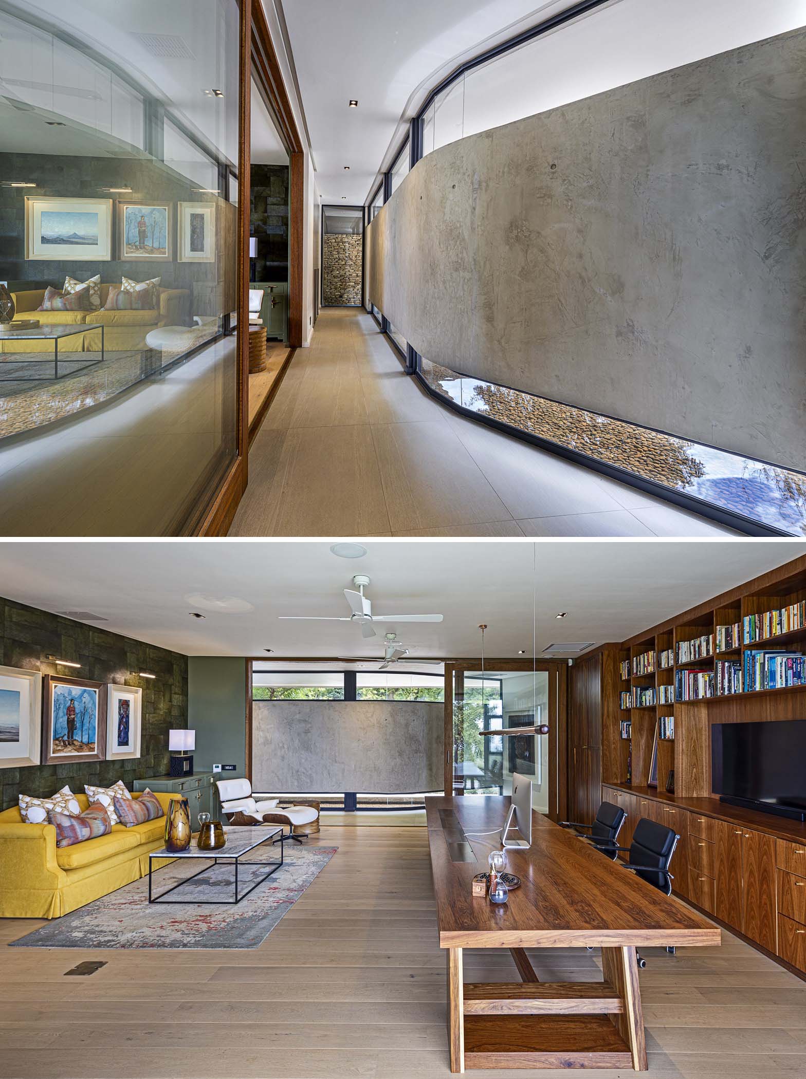 A home office down a hallway with a curved concrete wall includes a lounge area, large desk, and a custom wood wall unit with storage, shelving, and space for a TV.