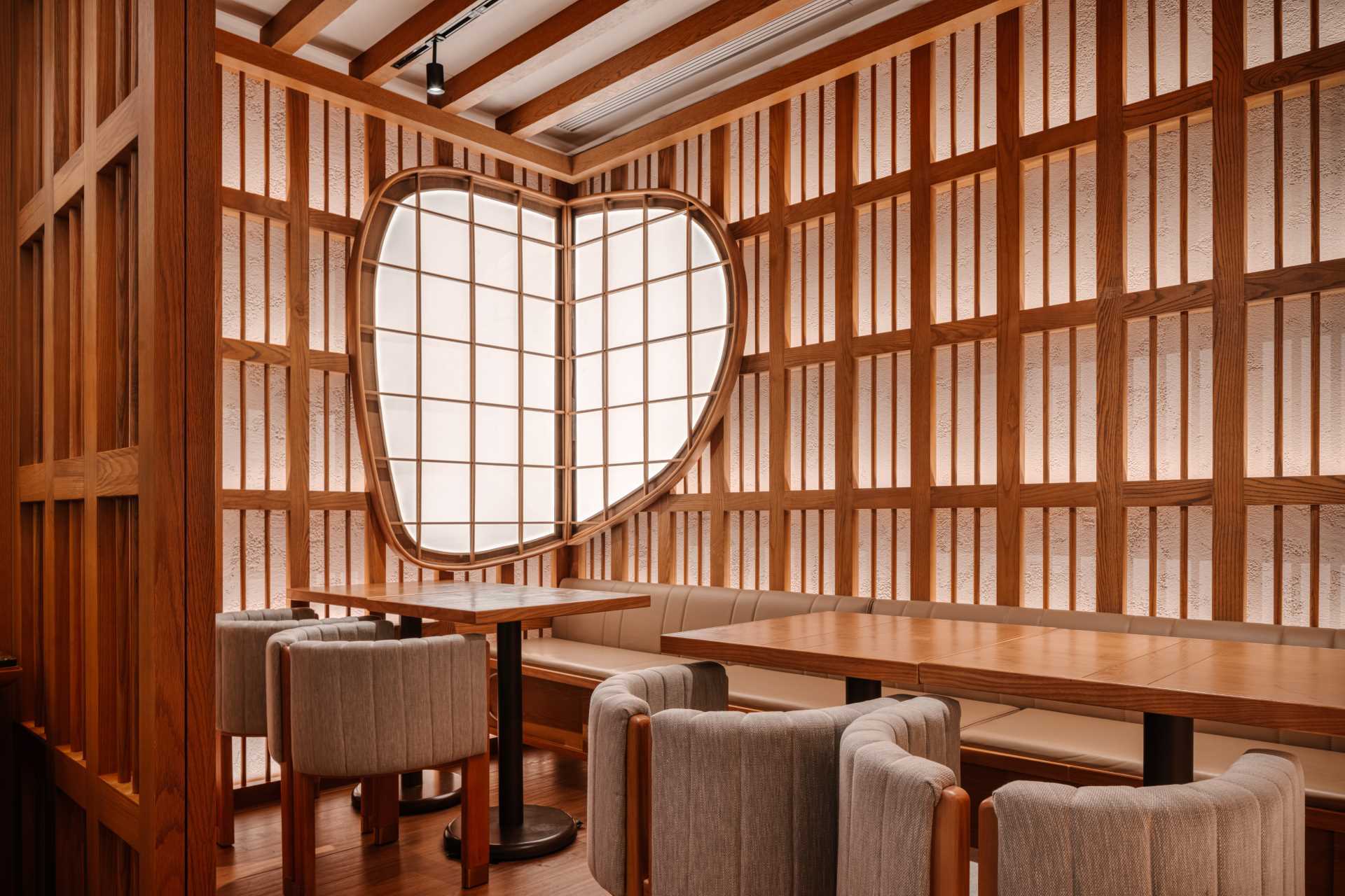 A private VIP dining room is decorated with an oval shoji window balancing the linear design of the wood accented walls.