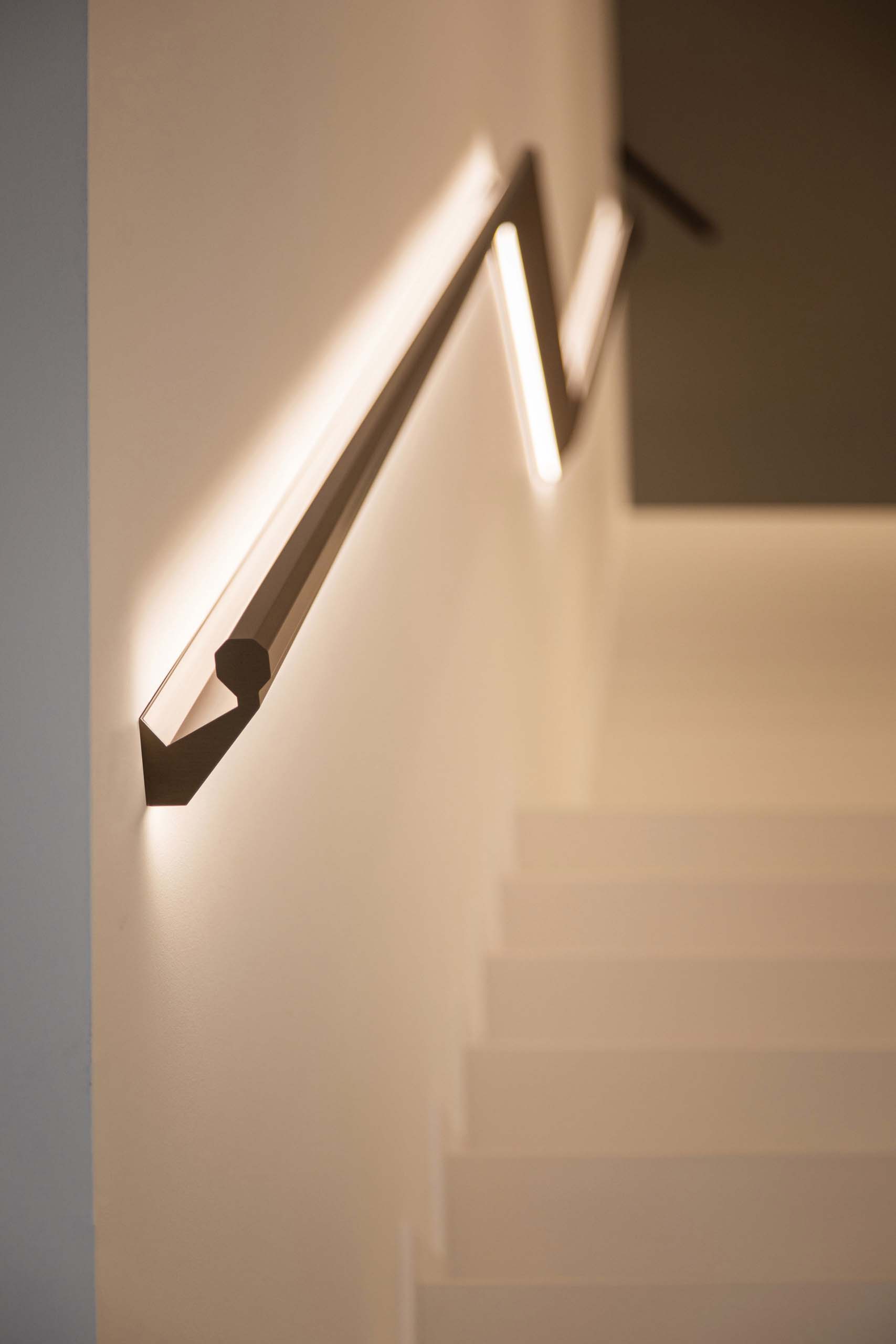 A modern staircase handrail designed with hidden LED lighting.