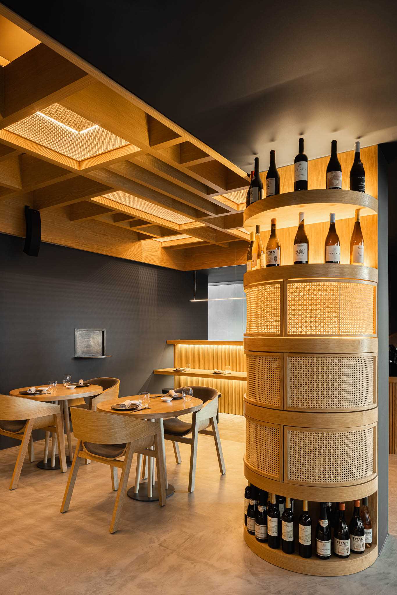 A modern restaurant with dark walls, wood accents, and straw panels.