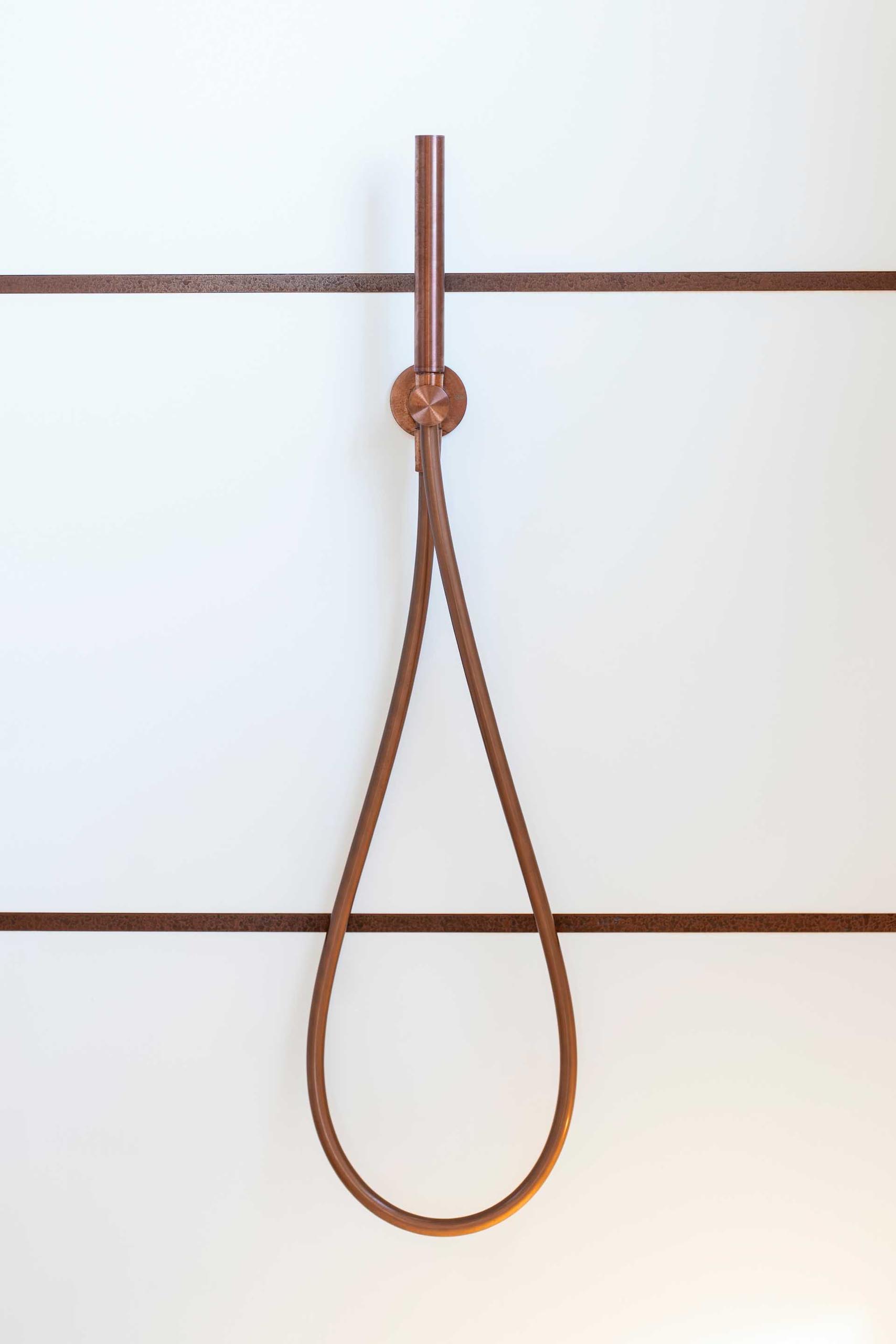 The horizontal copper lines and shower head in this shower complement the horizontal lines of the vanity.