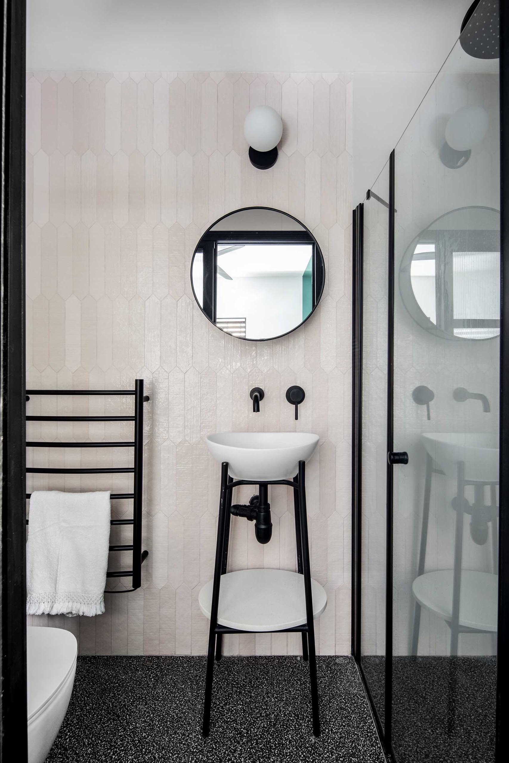 This modern bathroom includes pale pink tiles on the walls with black accents.