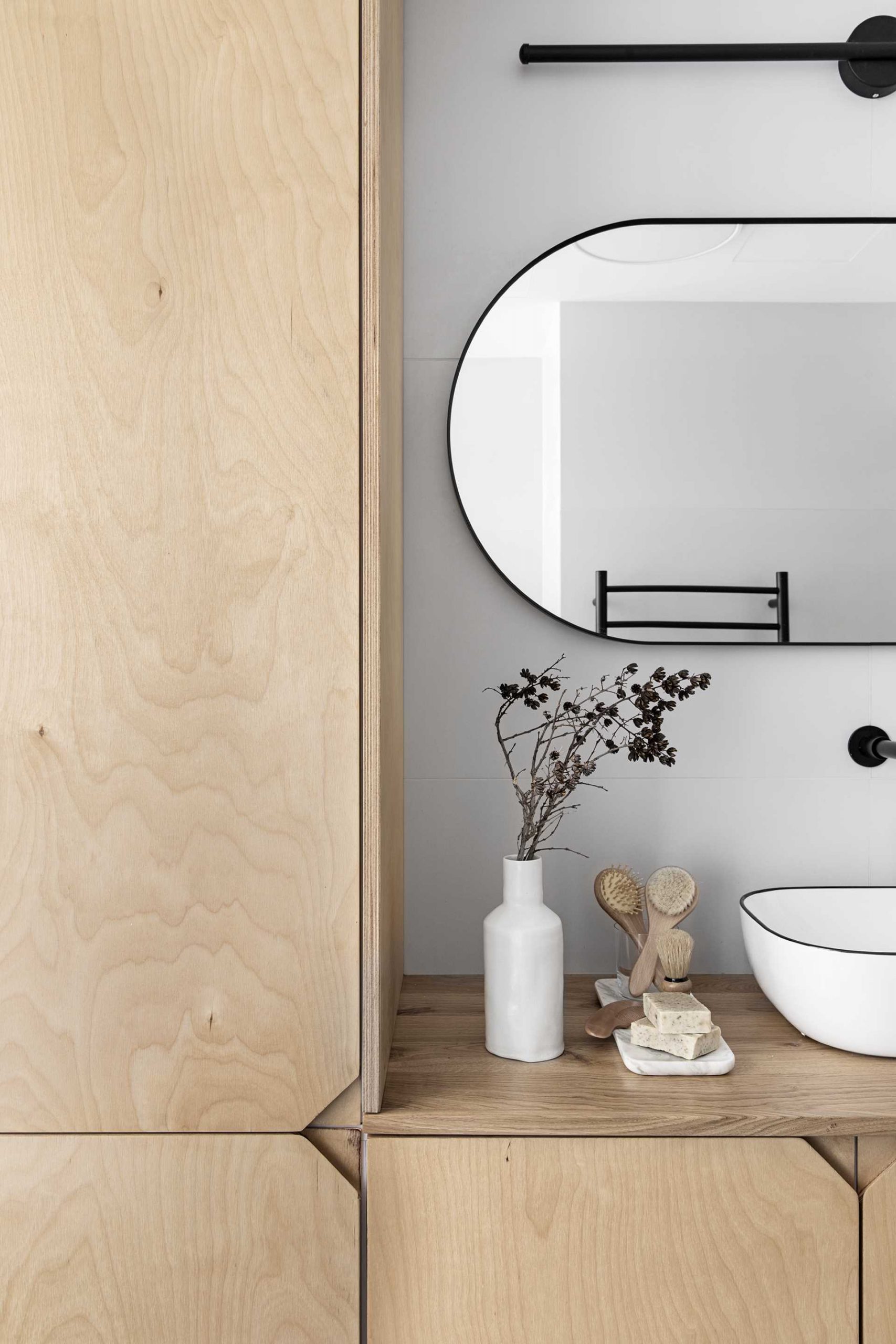 A modern bathroom with a wood vanity that includes cutouts instead of hardware.