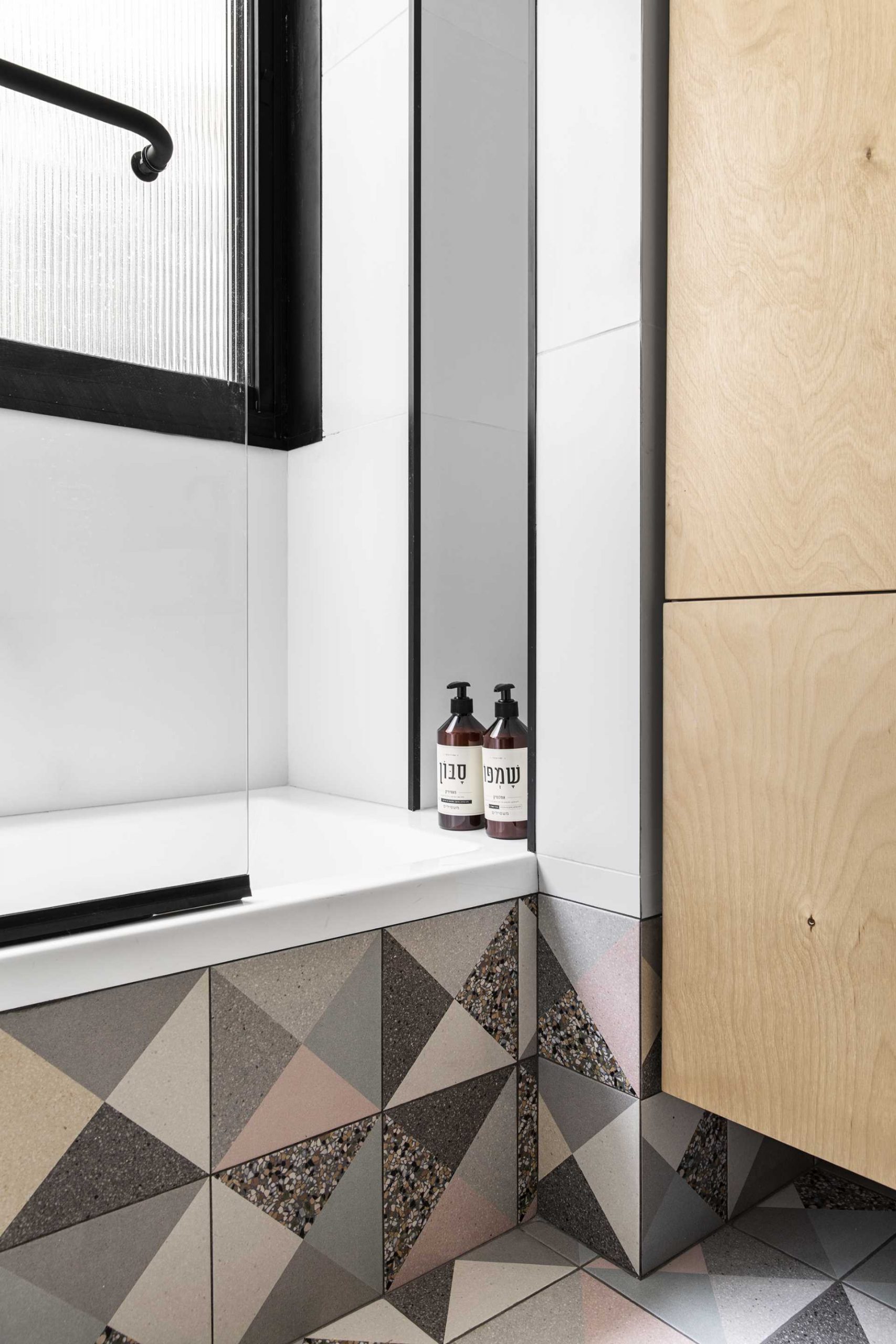 A modern bathroom with colorful geometric terrazzo tiles.