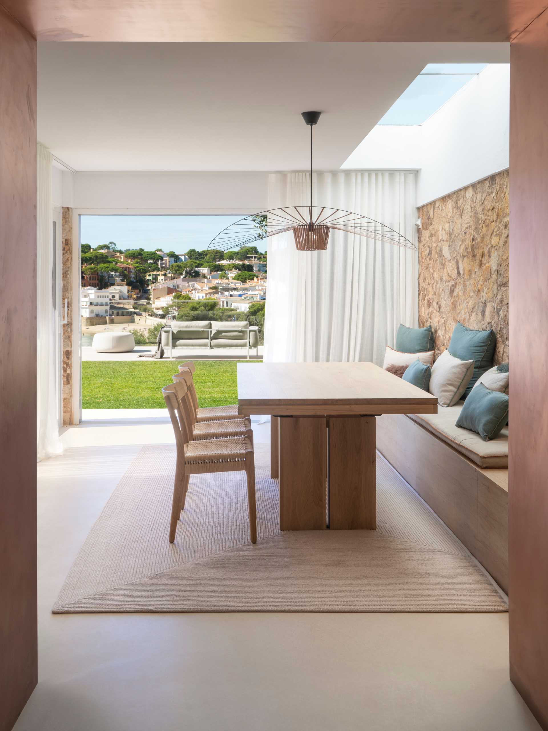 A modern dining room has a long built-in bench that acts as seating for the dining table.