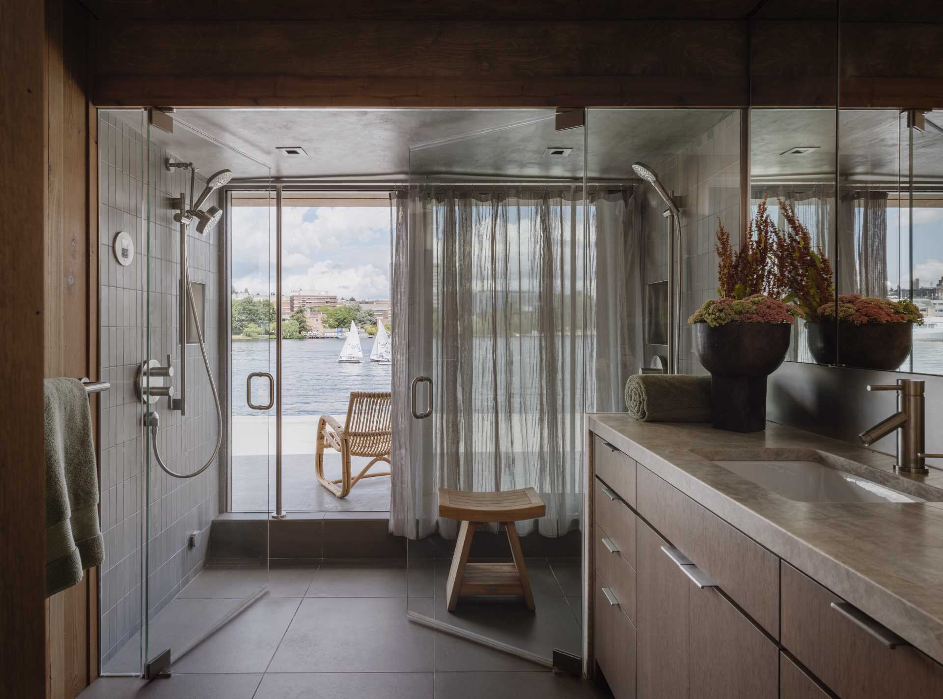 This primary bathroom features wood walls, while the dual shower has water views and tiled walls.