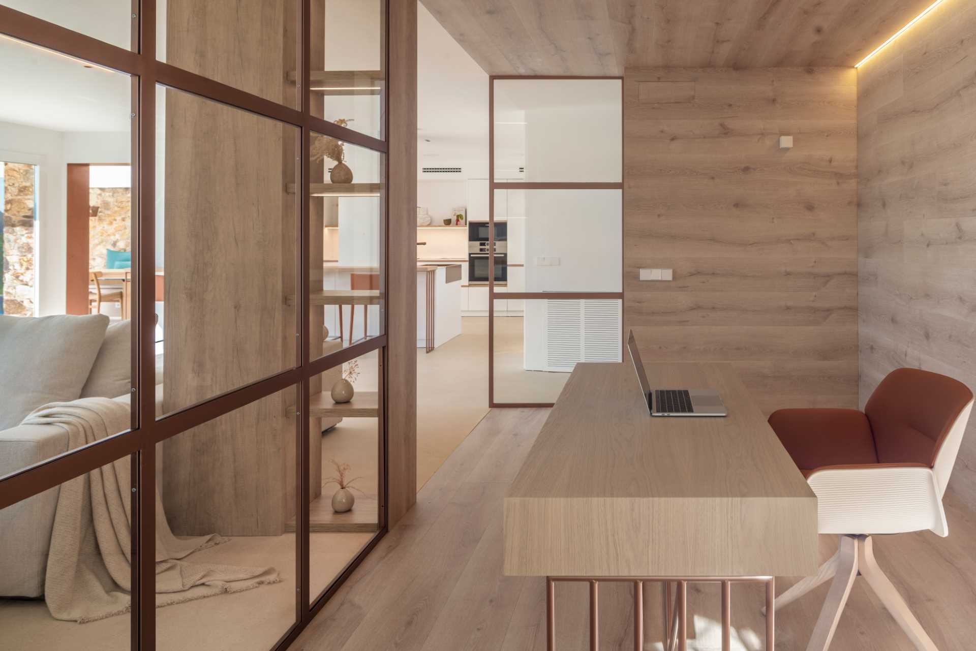 A modern home office lined with oak floors, walls, and ceilings, also includes copper-framed glass walls.