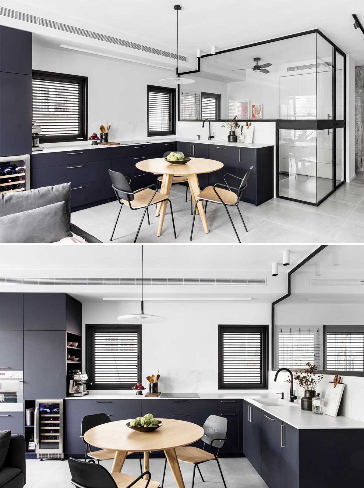 A modern matte black kitchen with a home office tucked away behind glass walls.