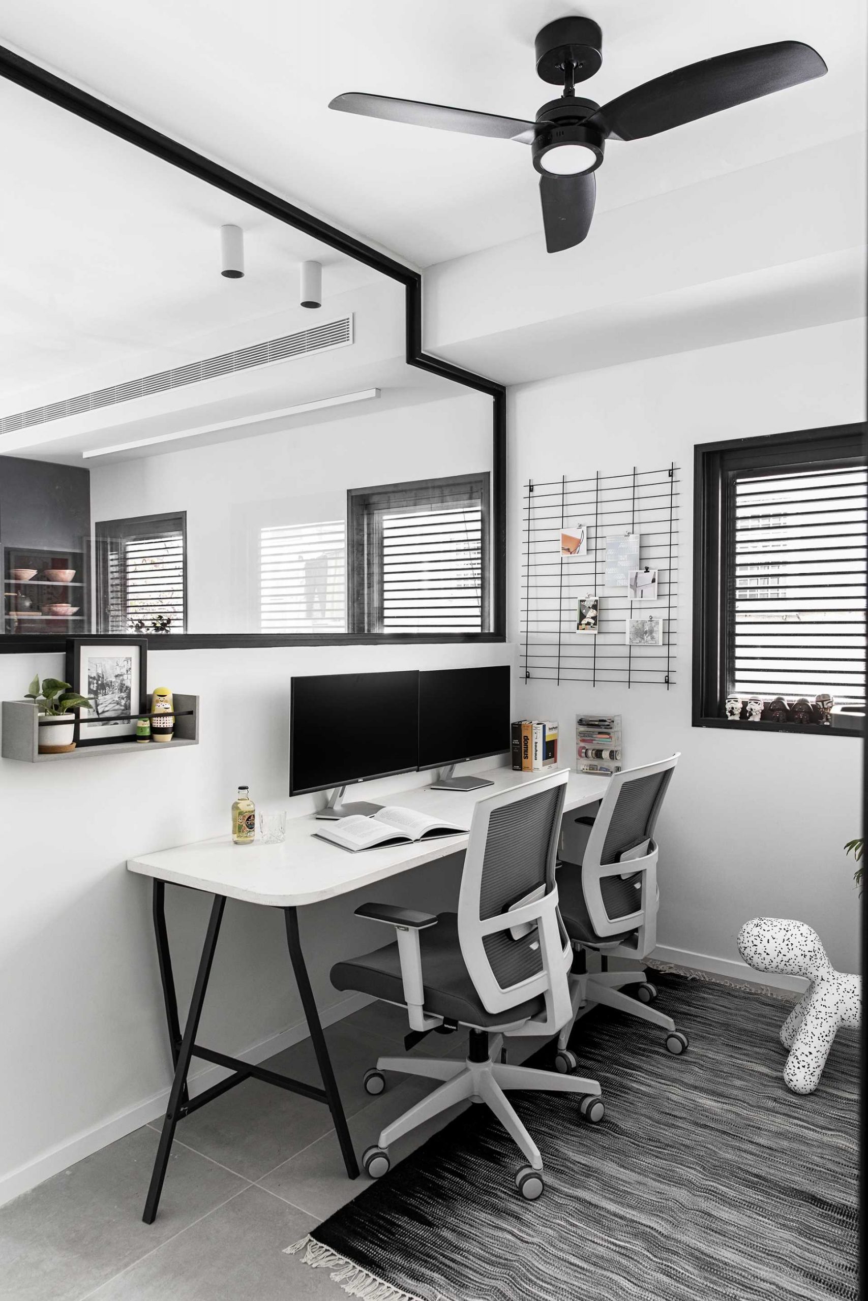 A modern home office with windows that provide views of the kitchen and living room.