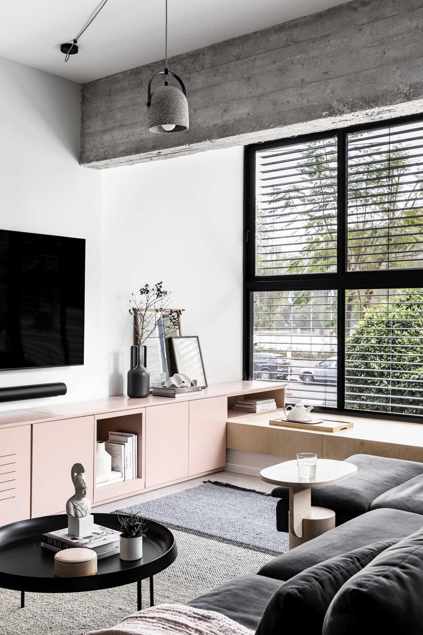 A modern living room with built-in cabinetry underneath the tv, and a wood window bench.